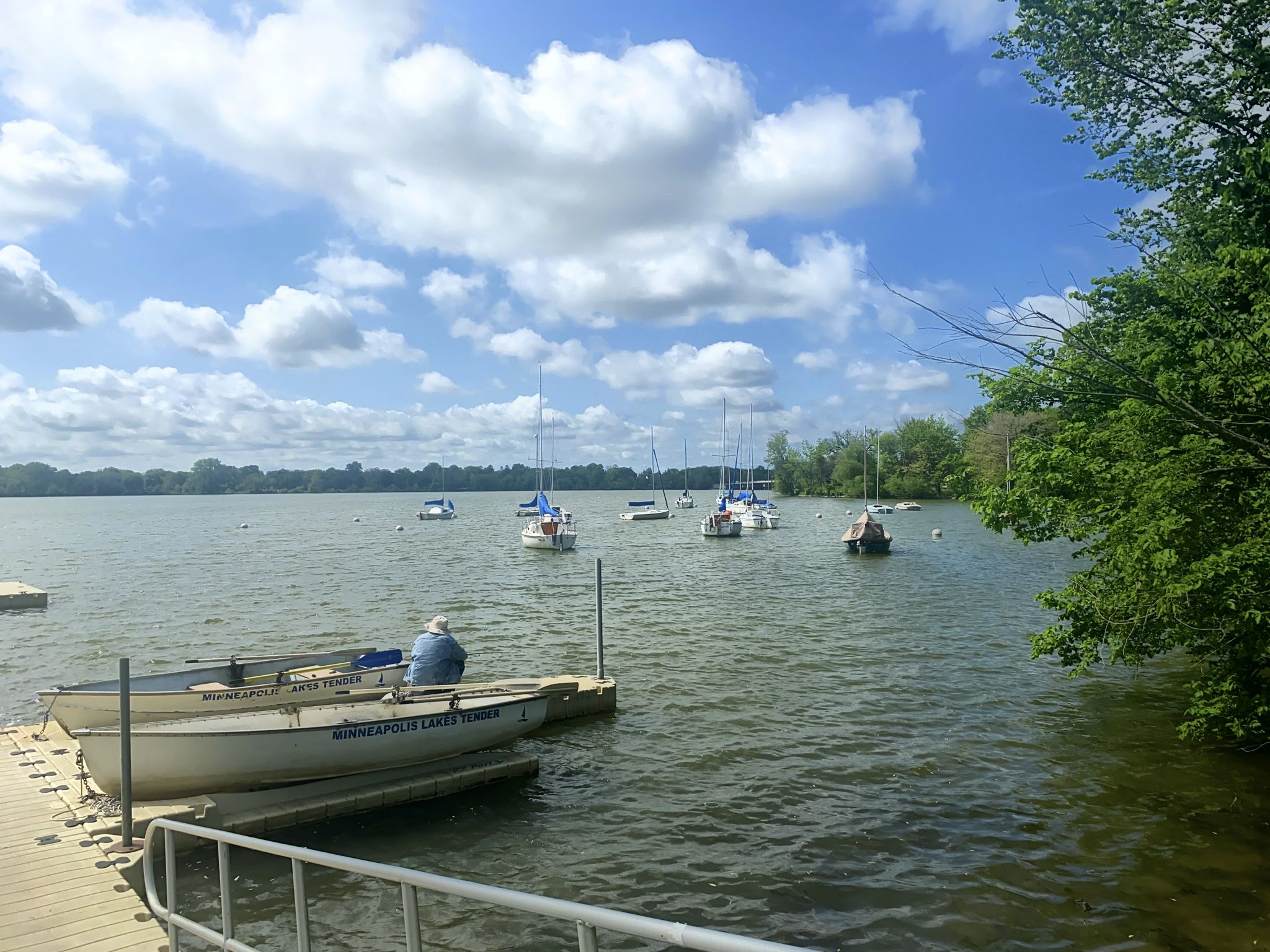Several boats anchored on a lake with a person on a dock. - Cottontail on the Trail – Lake Nokomis Pathway loop from Southwest