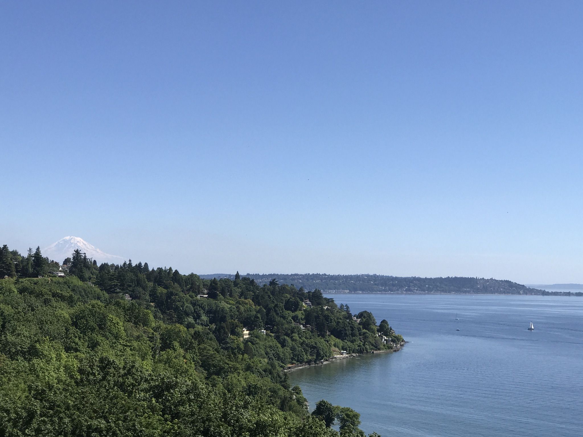 Panoramic view of water, forested hills, and a distant snow-capped mountain. - Discovery Park Loop Trail