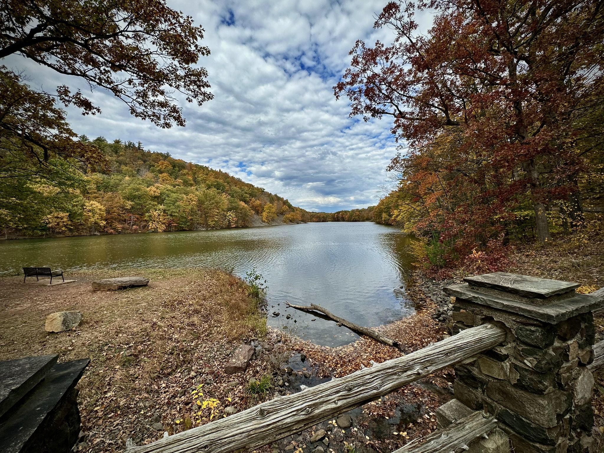Lake surrounded by autumn trees and hills under a cloudy sky. - View of Reservoir Number 3 Dam loop from West Hartford Reservoirs Recreation Area
