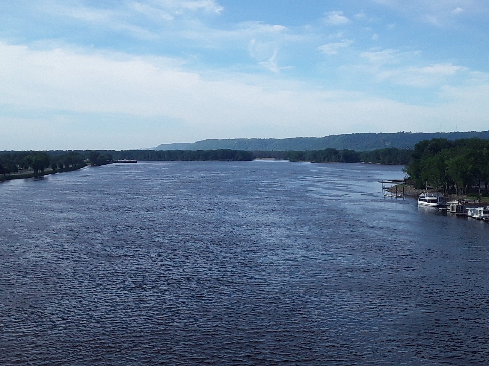 A wide river with distant forested hills under a partly cloudy sky. - Mississippi River & Apple Blossom Scenic Byway loop