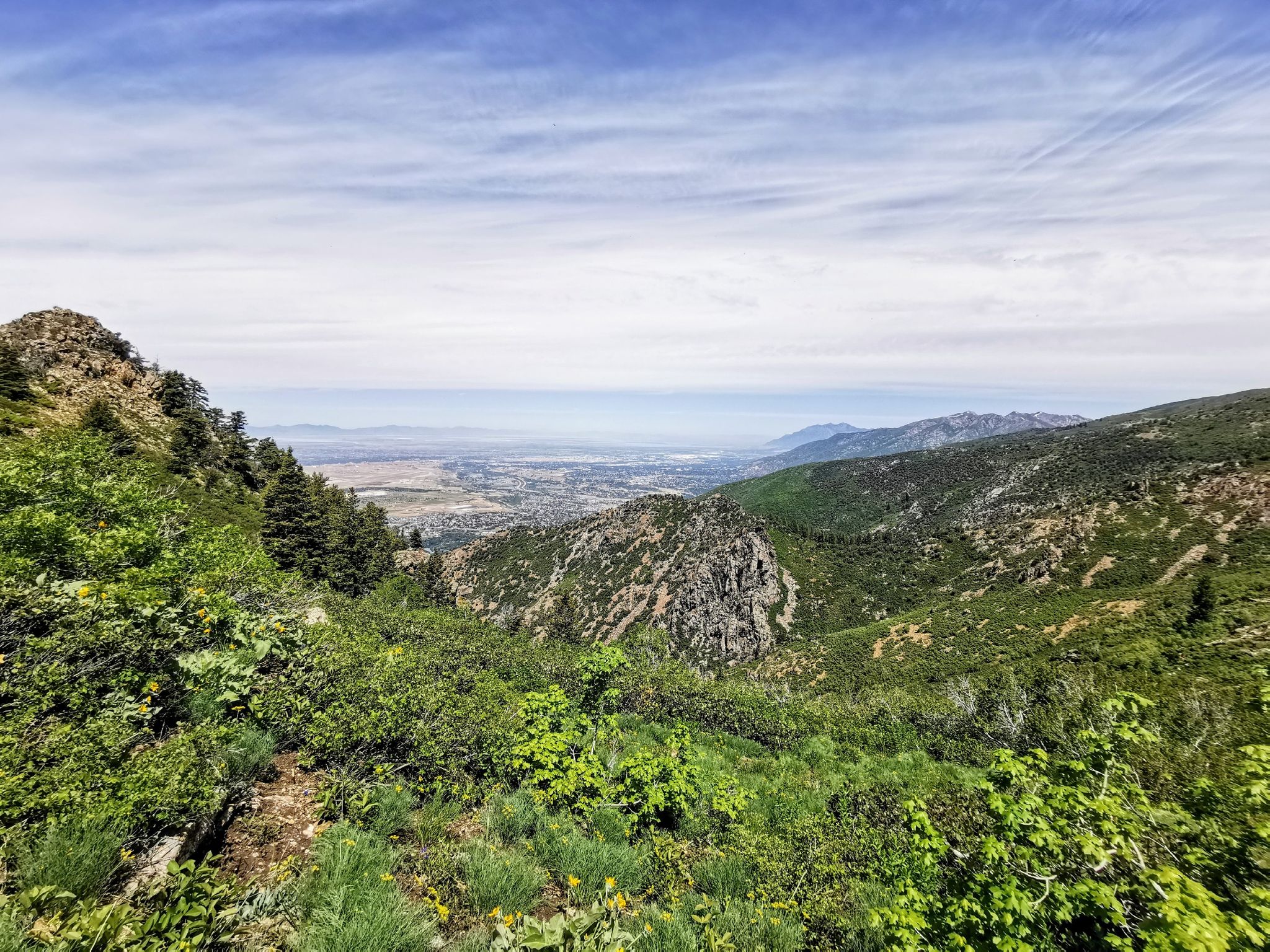 Green mountains and valley with a distant city under a cloudy sky. - Thurston Peak via Adams Cabin Trail