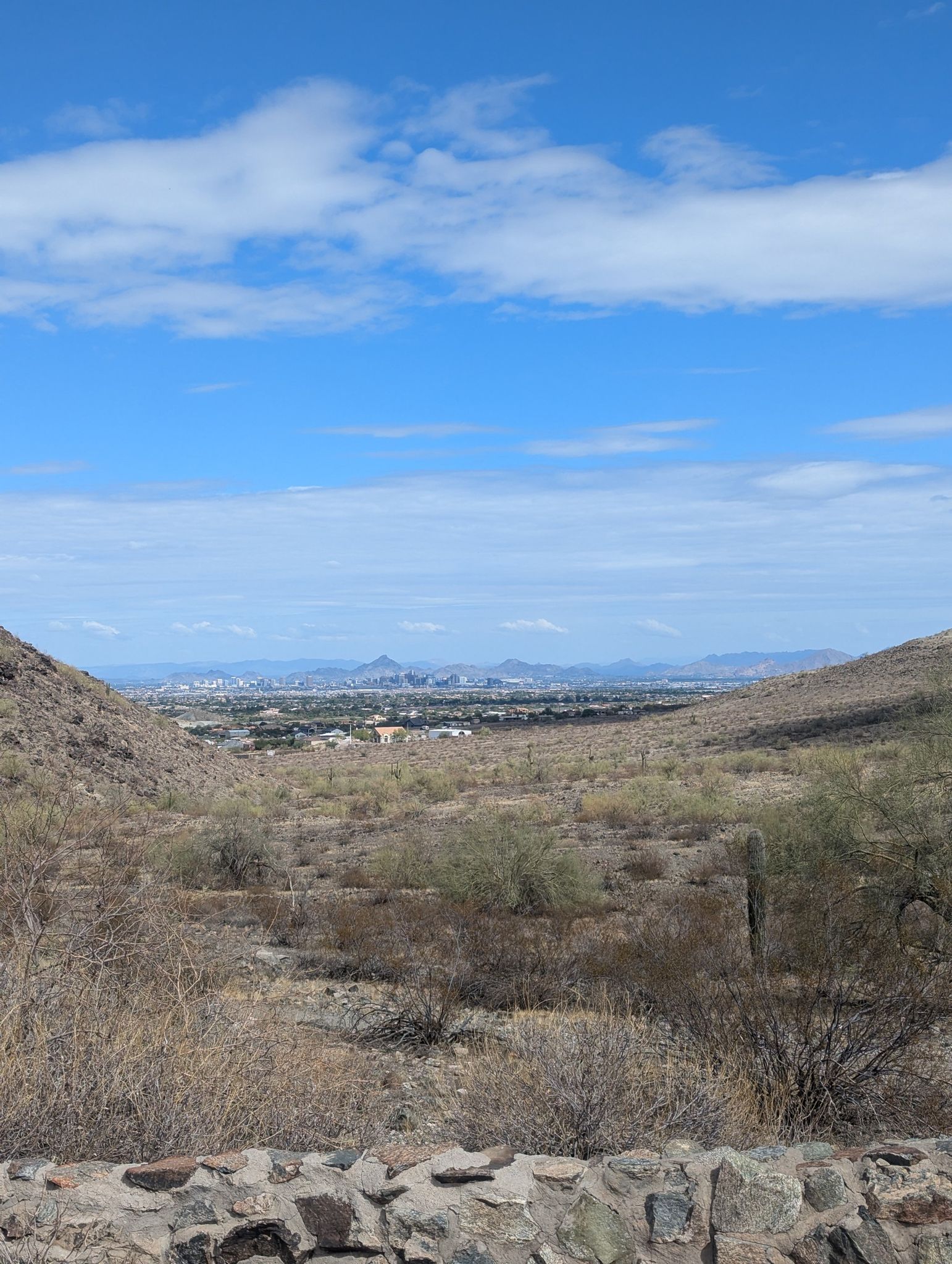 Desert landscape with distant city, mountains, and blue sky with clouds. - Alta-Bajada Loop