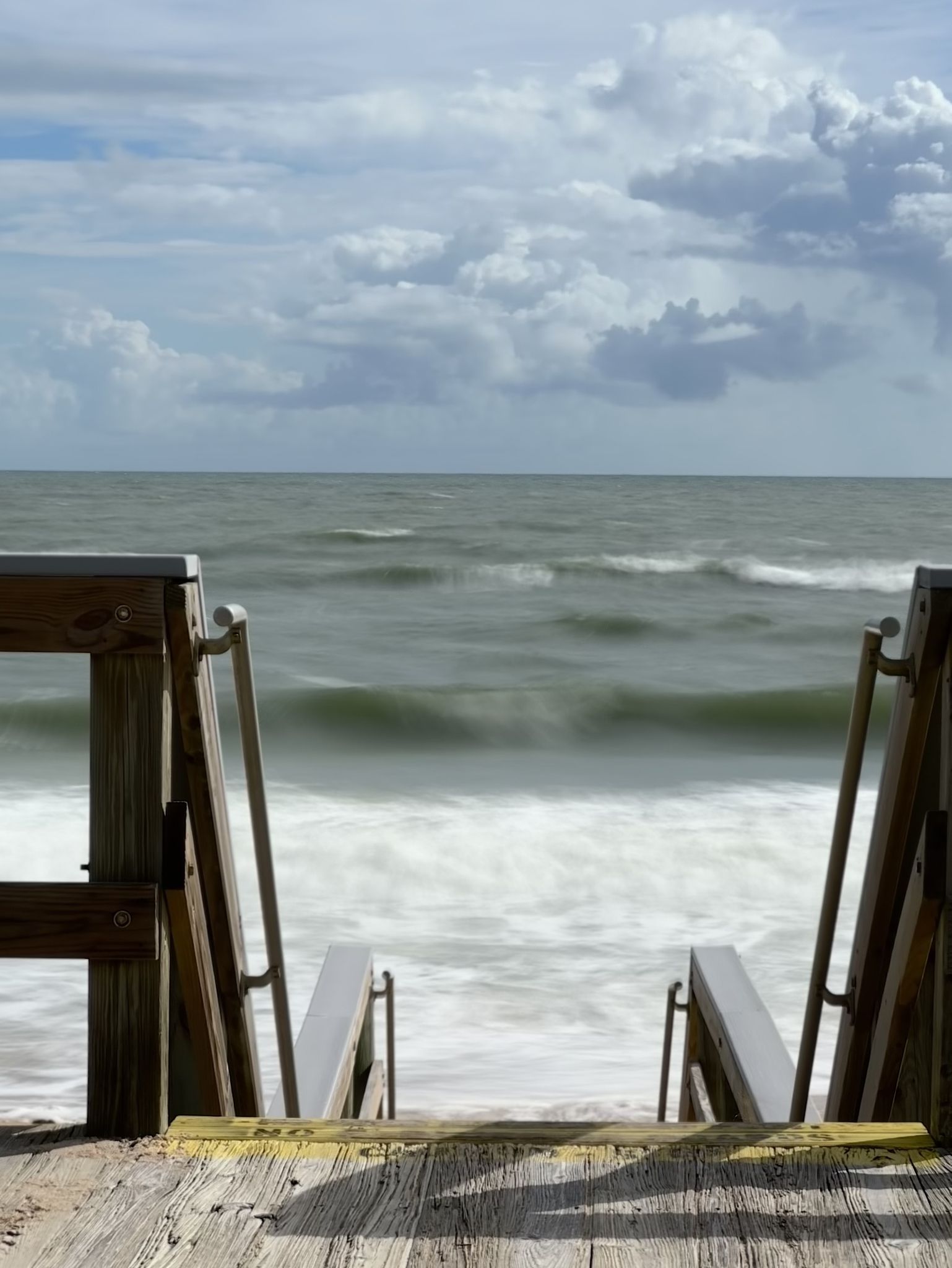 Wooden boardwalk steps leading to a wavy ocean under a cloudy sky. - Ormond Beach to Flagler Beach Scenic Drive