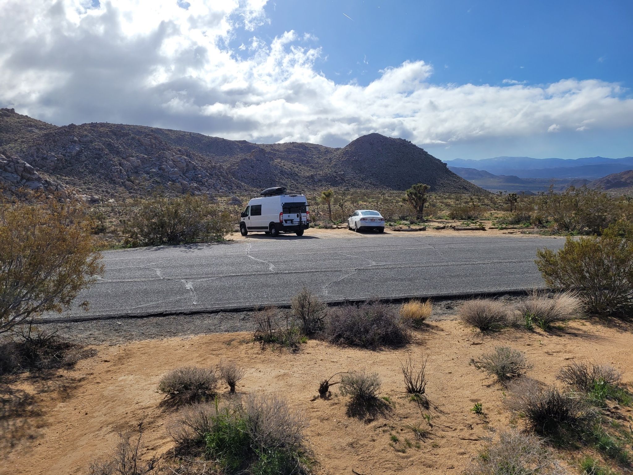 Camper van and car parked on a desert lot with mountains in background. - Bigfoot and Panorama Loop