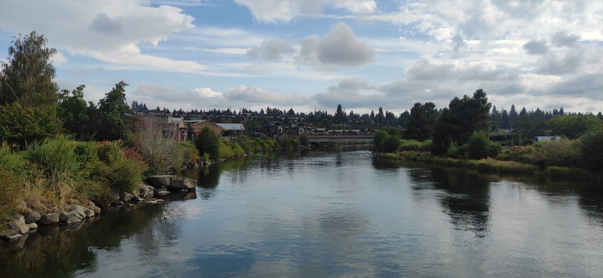 Wide river reflecting cloudy sky, with distant buildings and trees. - Drake Park – Farewell Bend Park loop from Drake Park Neighborhood Historic District