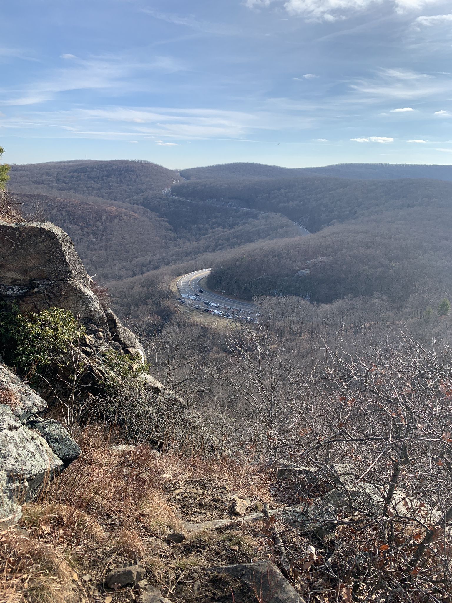 Rocky cliff overlooking a winding road in a valley with distant hills. - Butter Hill and Storm King Mountain Loop