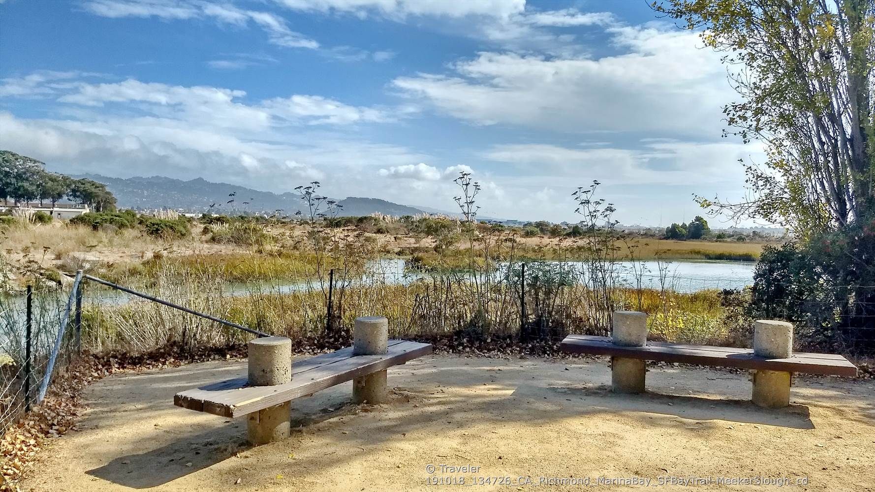 Two rustic benches on a dirt path overlooking marshy water and distant hills. - Shimada Friendship Park – Meeker Slough Bike Trail loop from Rosie the Riveter/World War II Home Front National Historical Park