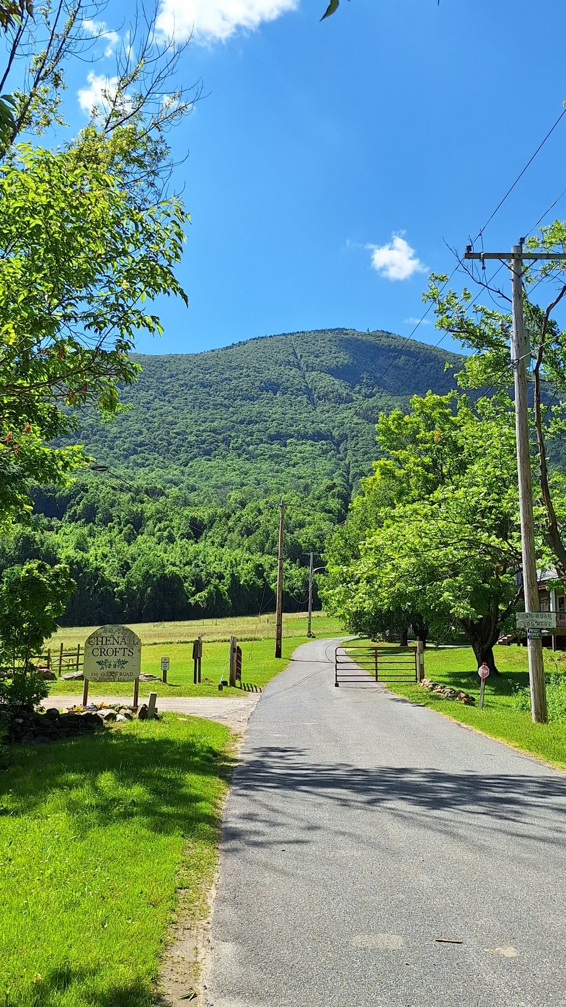 Paved road leads to a gate with a lush green mountain beyond. - Mount Greylock Loop via Bellows Pipe and Gould Trail