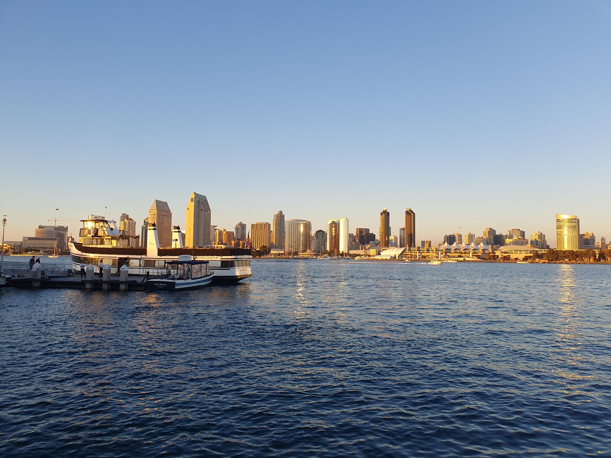 Boats docked near a city skyline across water during golden hour. - View of Downtown San Diego – Coronado Ferry Landing loop from Coronado