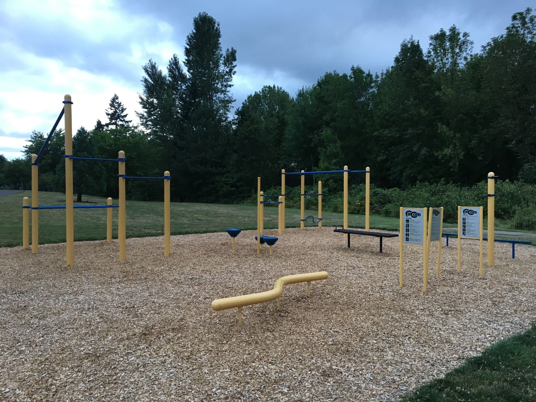 Outdoor fitness equipment on wood chips under a cloudy sky. - Fanno Creek Trail – Fanno Creek Trail loop from Beaverton