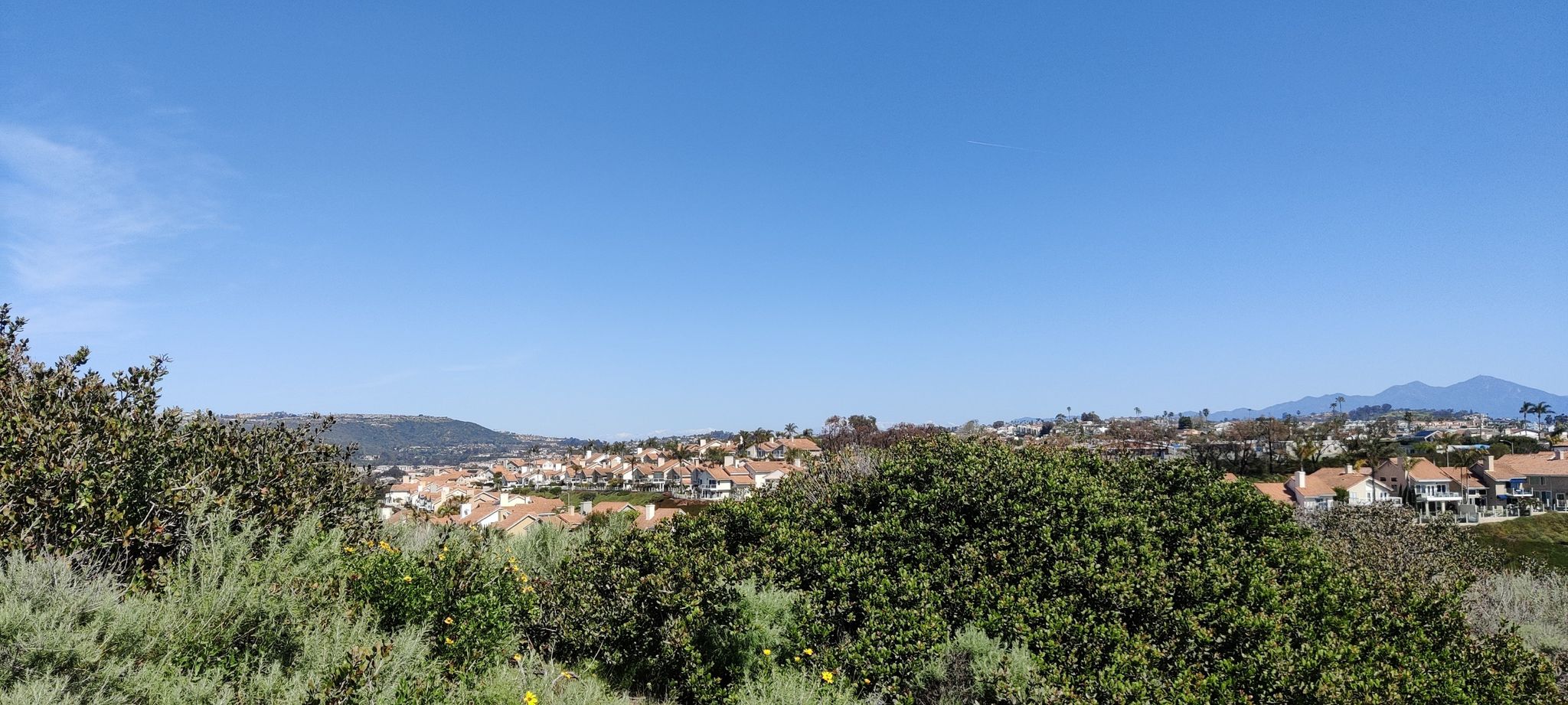 Panoramic view of a distant town nestled among green hills under clear sky. - San Juan Creek Trail and Dana Point Harbor Loop
