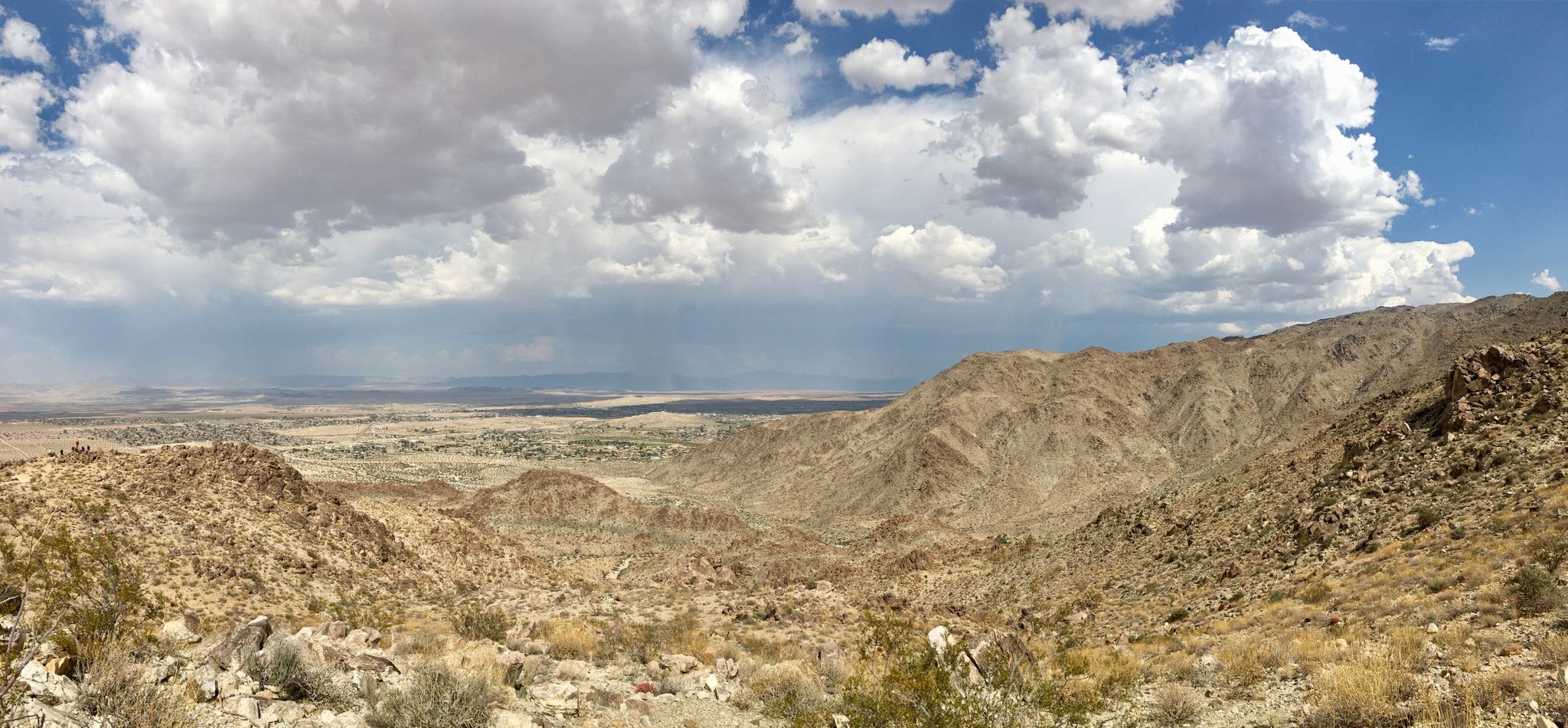 Panoramic view of a vast desert valley with distant mountains under cloudy sky. - Fortynine Palms Oasis Trail
