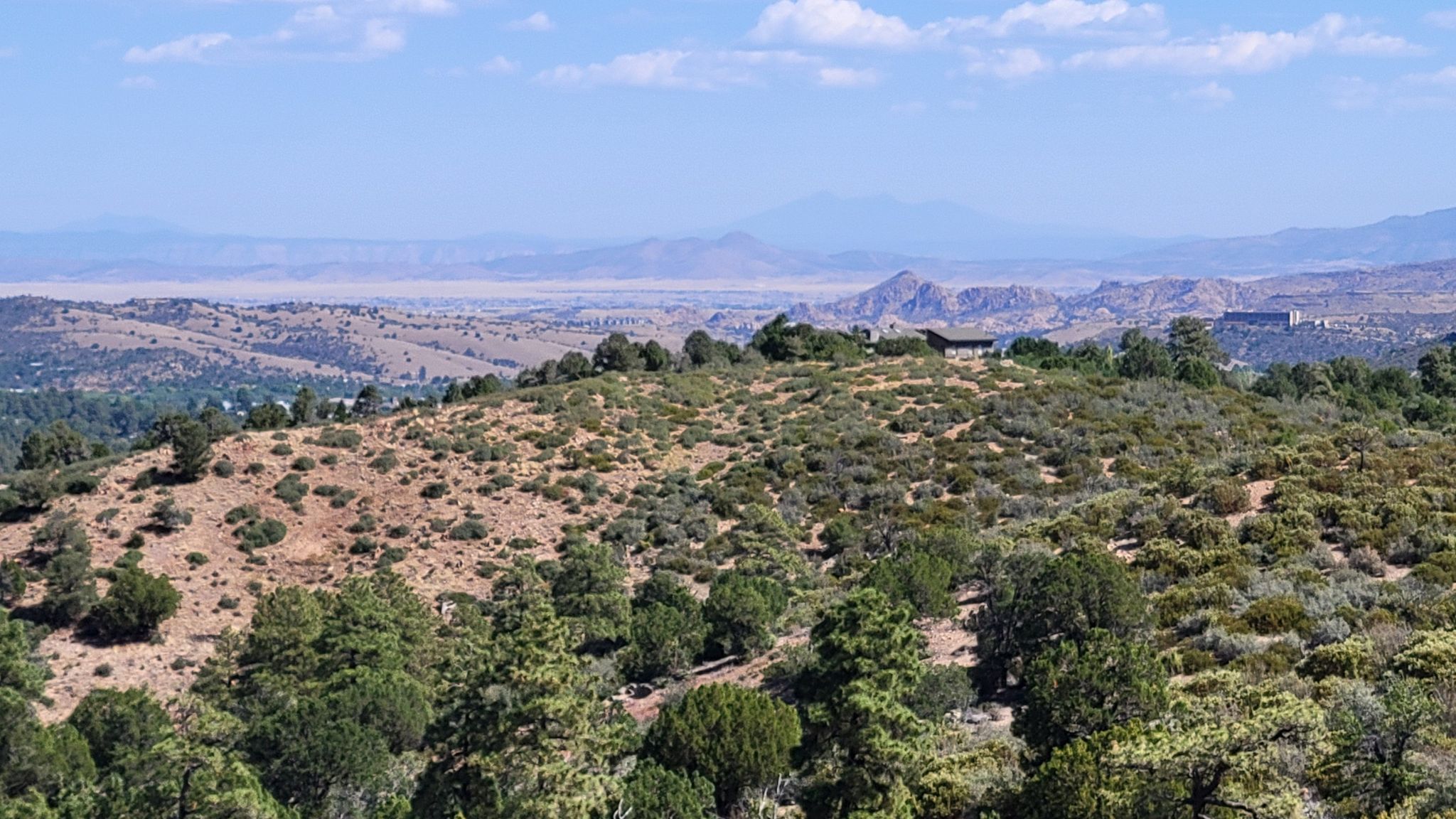 Hilly landscape with sparse vegetation, distant mountains under a partly cloudy sky. - Wolverton Trail loop from Aspen Creek Trailhead Parking Lot