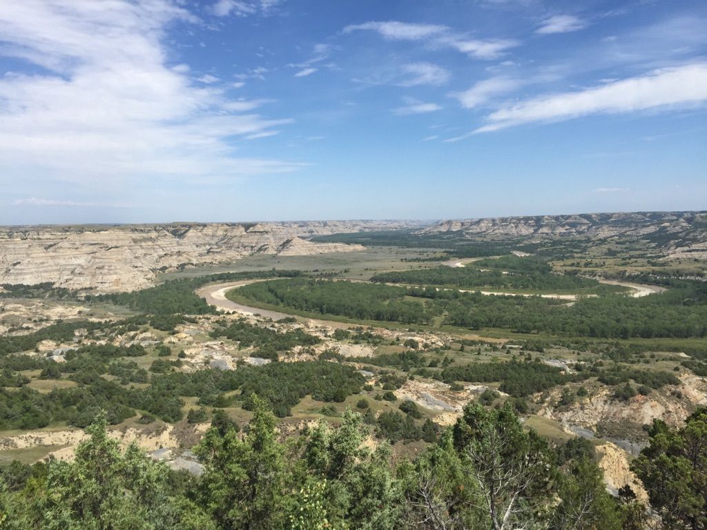 Wide view of a winding river through a green valley under a blue sky. - Achenbach Trail Loop