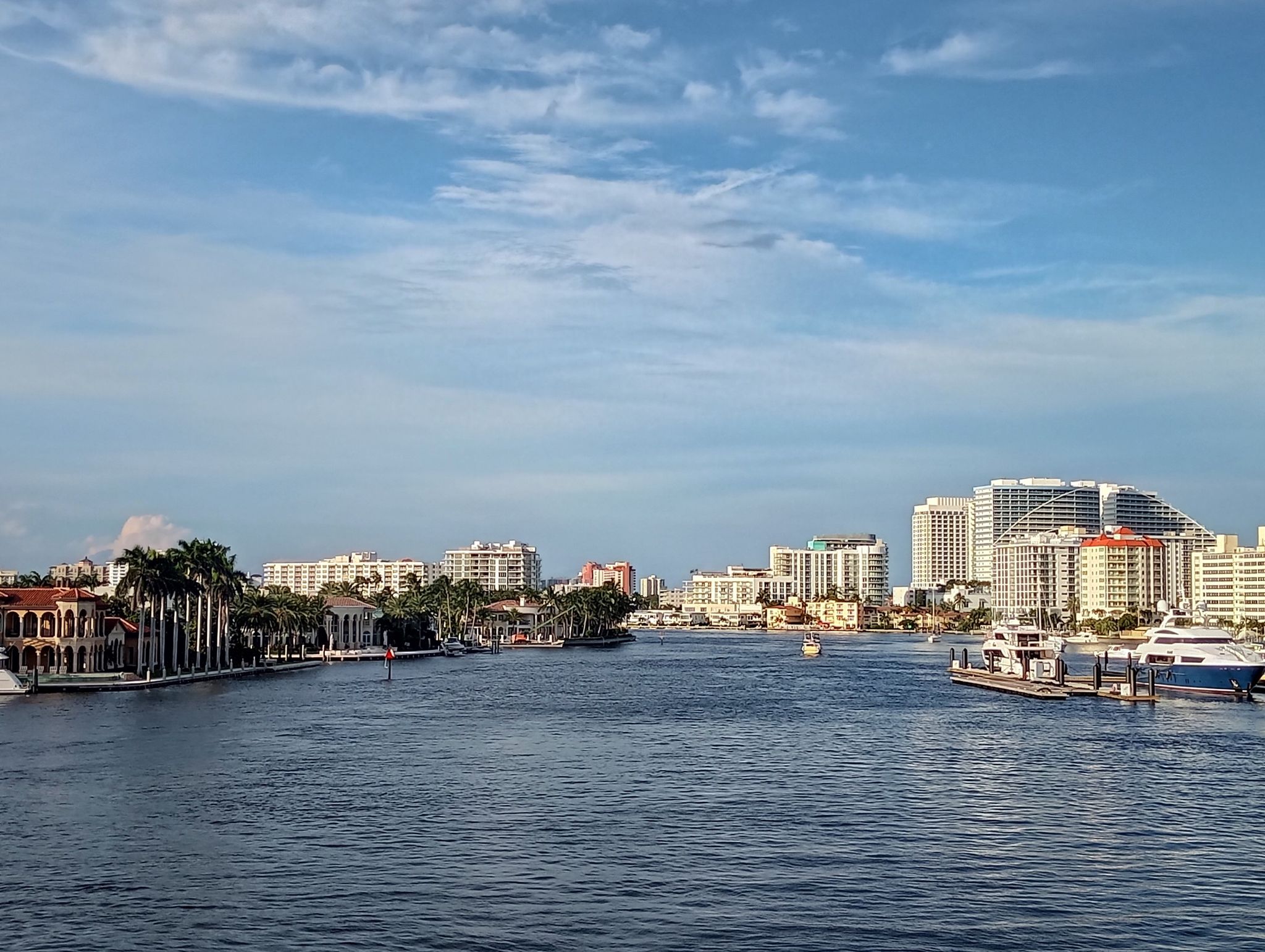 City skyline and waterfront homes along a wide river under a cloudy sky. - Barrier Islands Greenway Loop