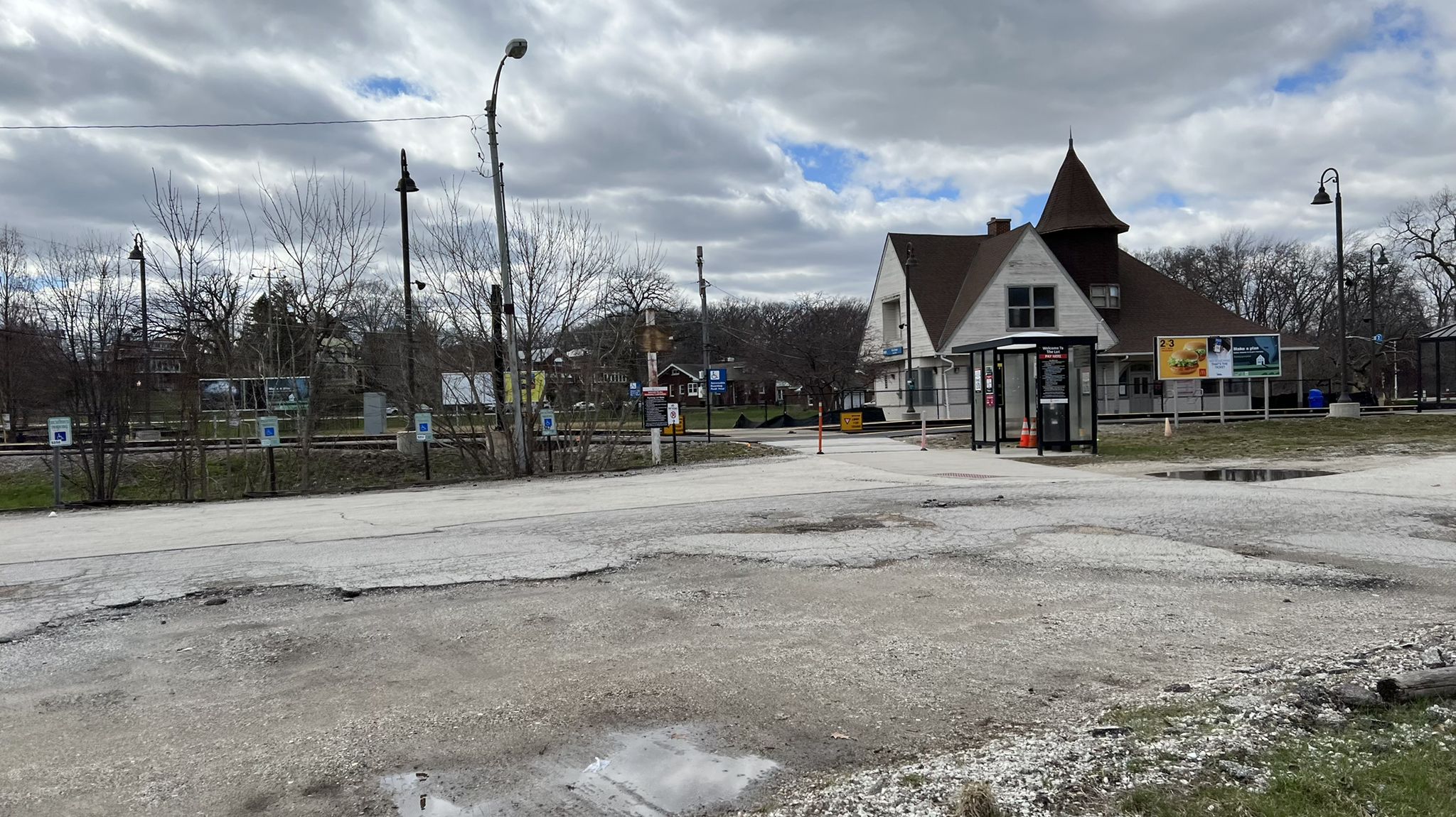 Overcast view of a building, bus stop, and wet road with puddles. - Major Taylor Trail – Whistler Woods loop from Wrightwood
