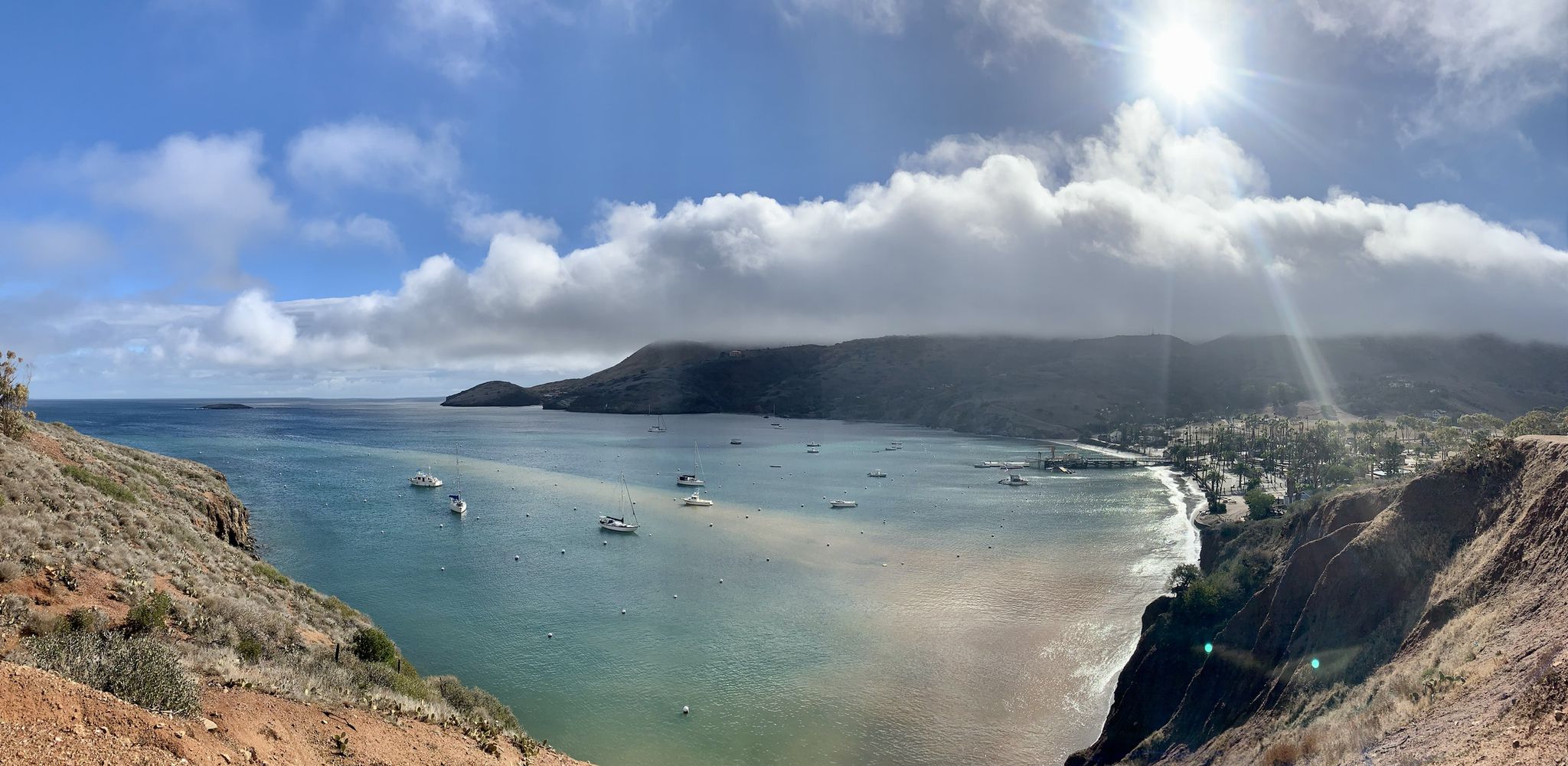 Panoramic view of a sunny bay with boats, a beach, and a coastal town. - Lion Head – Sullivans Beach loop from Santa Catalina Island