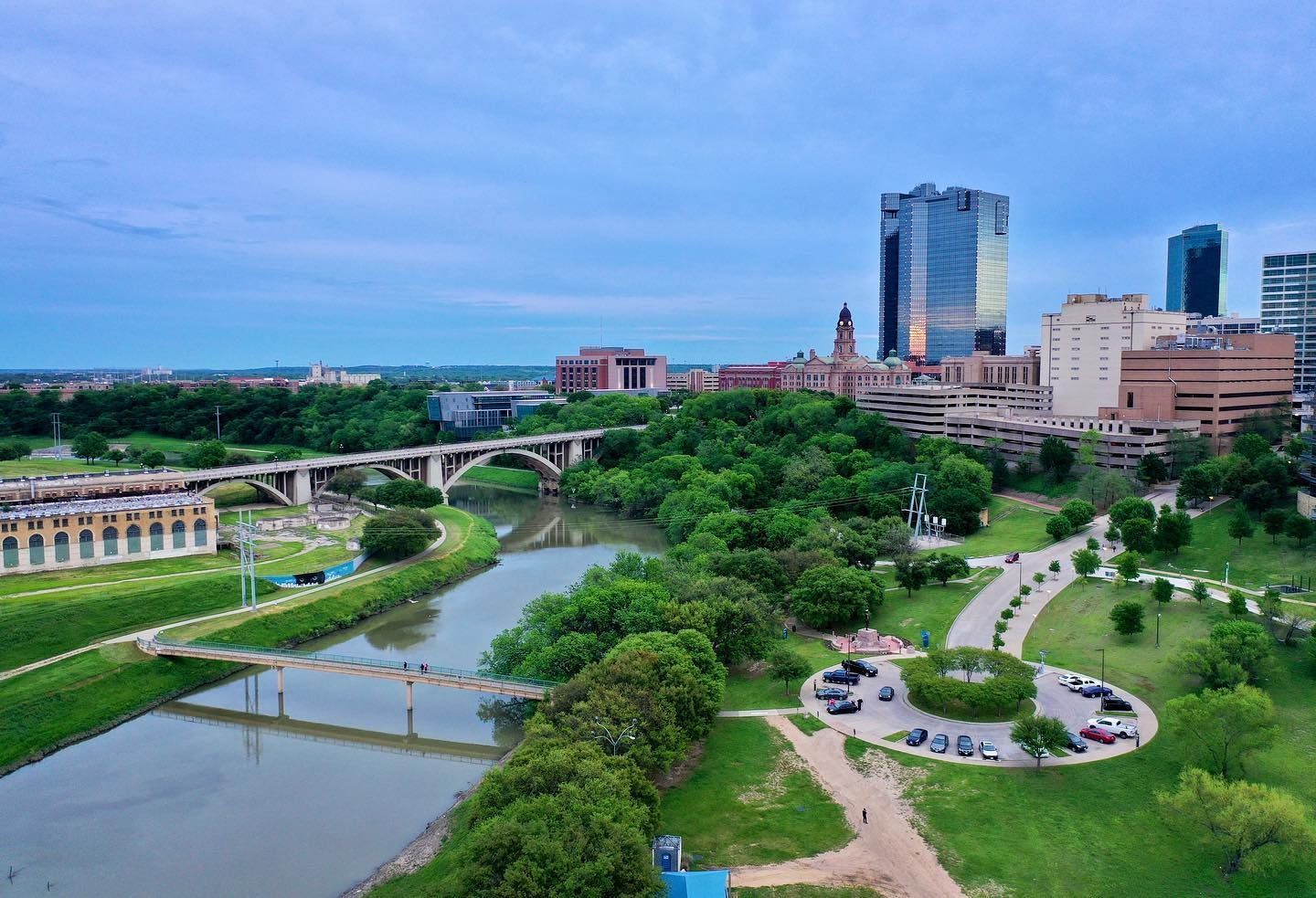 Aerial view of a city skyline, river, and bridges under a blue sky. - Trinity Trails