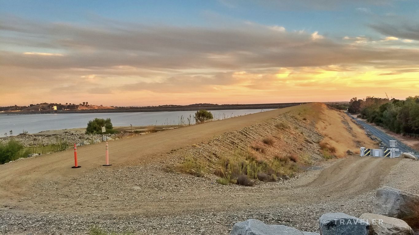 Wide dirt path next to calm water at sunset with warm sky. - Granite Bay loop