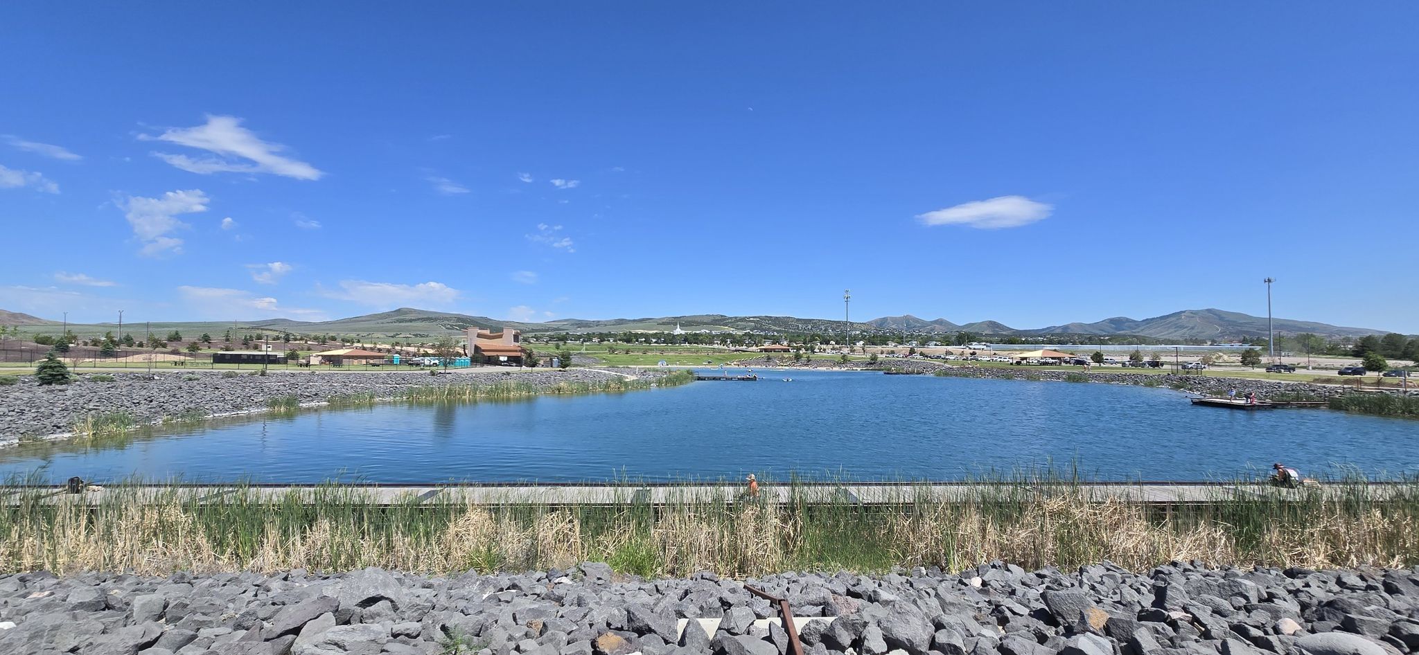 Wide shot of a blue lake with rocky banks, distant mountains under clear sky. - Portneuf Wellness Complex Loop