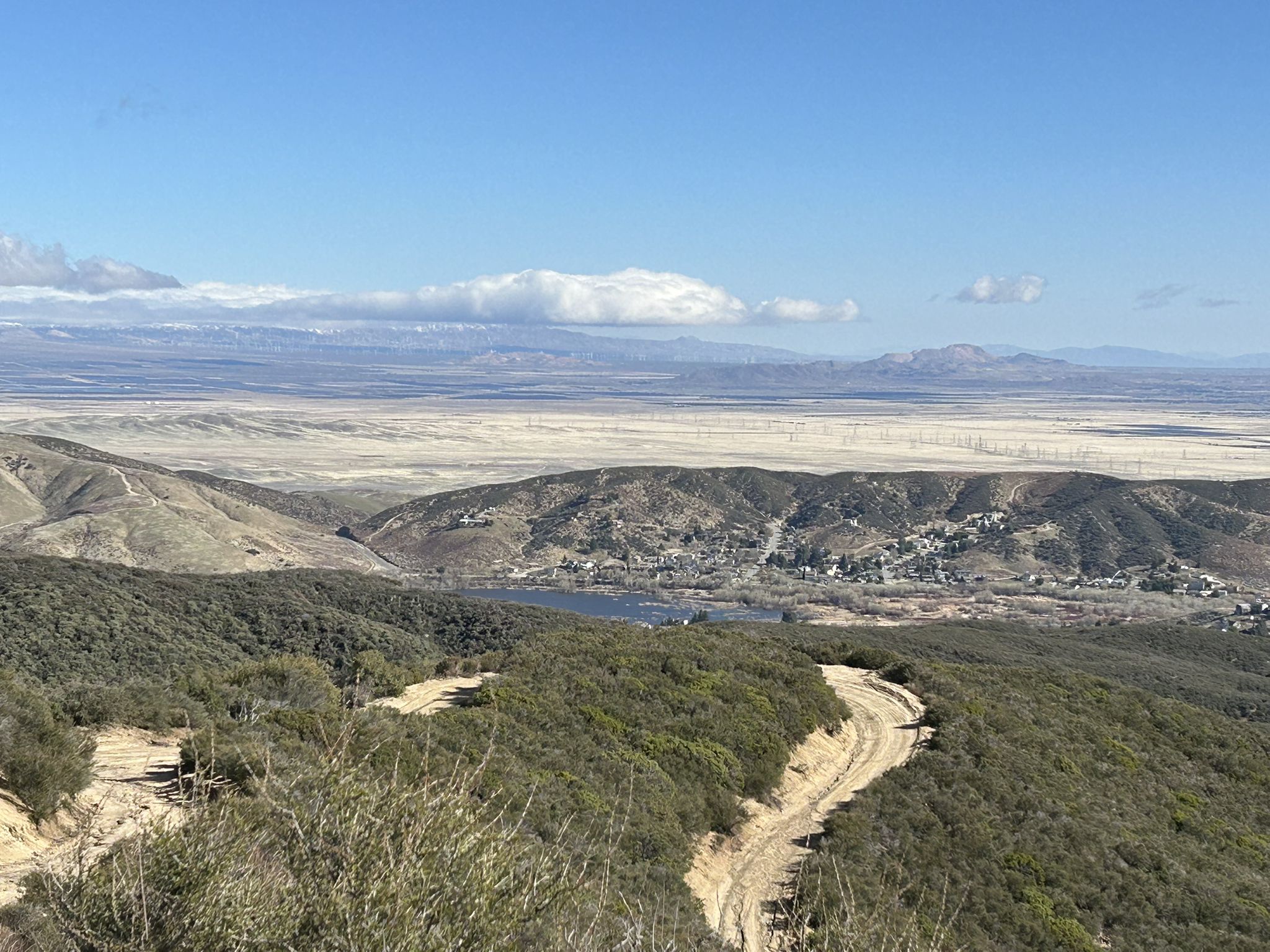 Winding dirt road on a scrubby hillside overlooking a valley and distant mountains. - Grass Mountain Loop via PCT and Firebreak