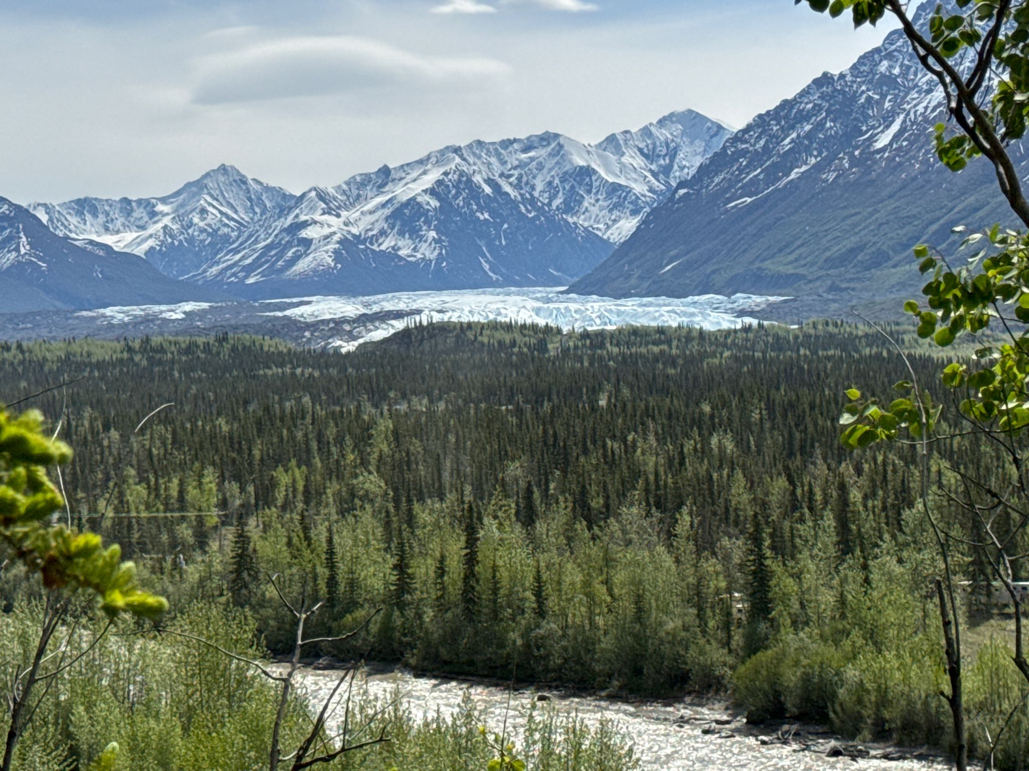 Glacier nestled in a valley with dense forest and snow-capped mountains. - Edge Nature Trail