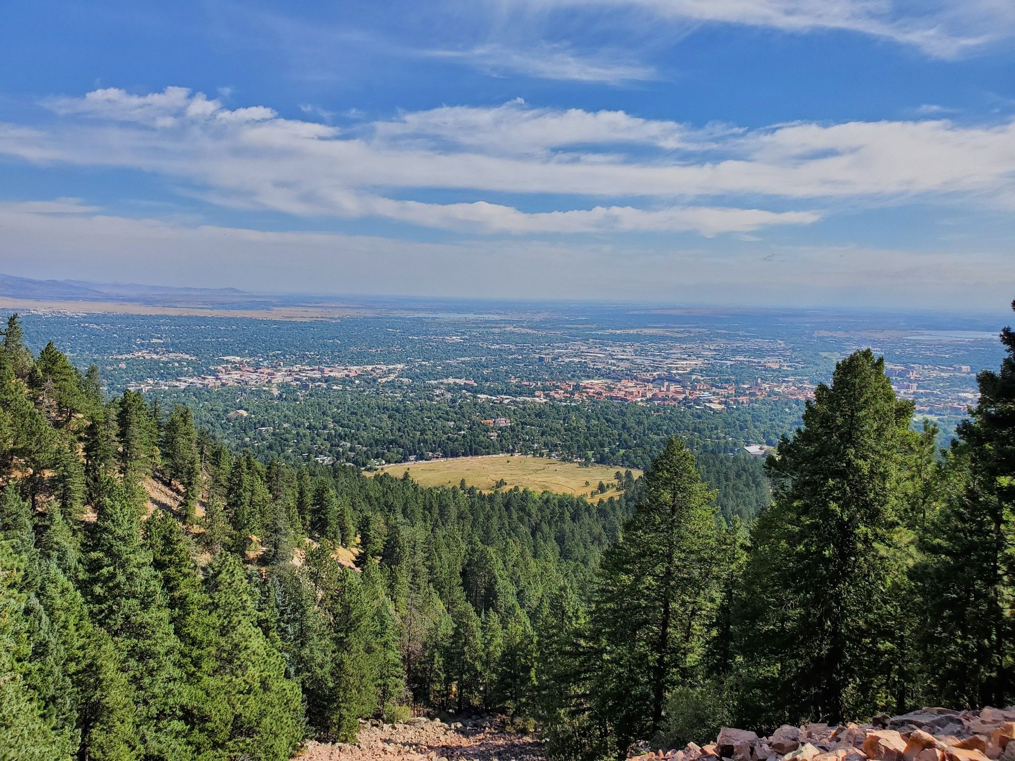 Elevated view of a city surrounded by forests under a blue sky. - First and Second Flatirons Loop