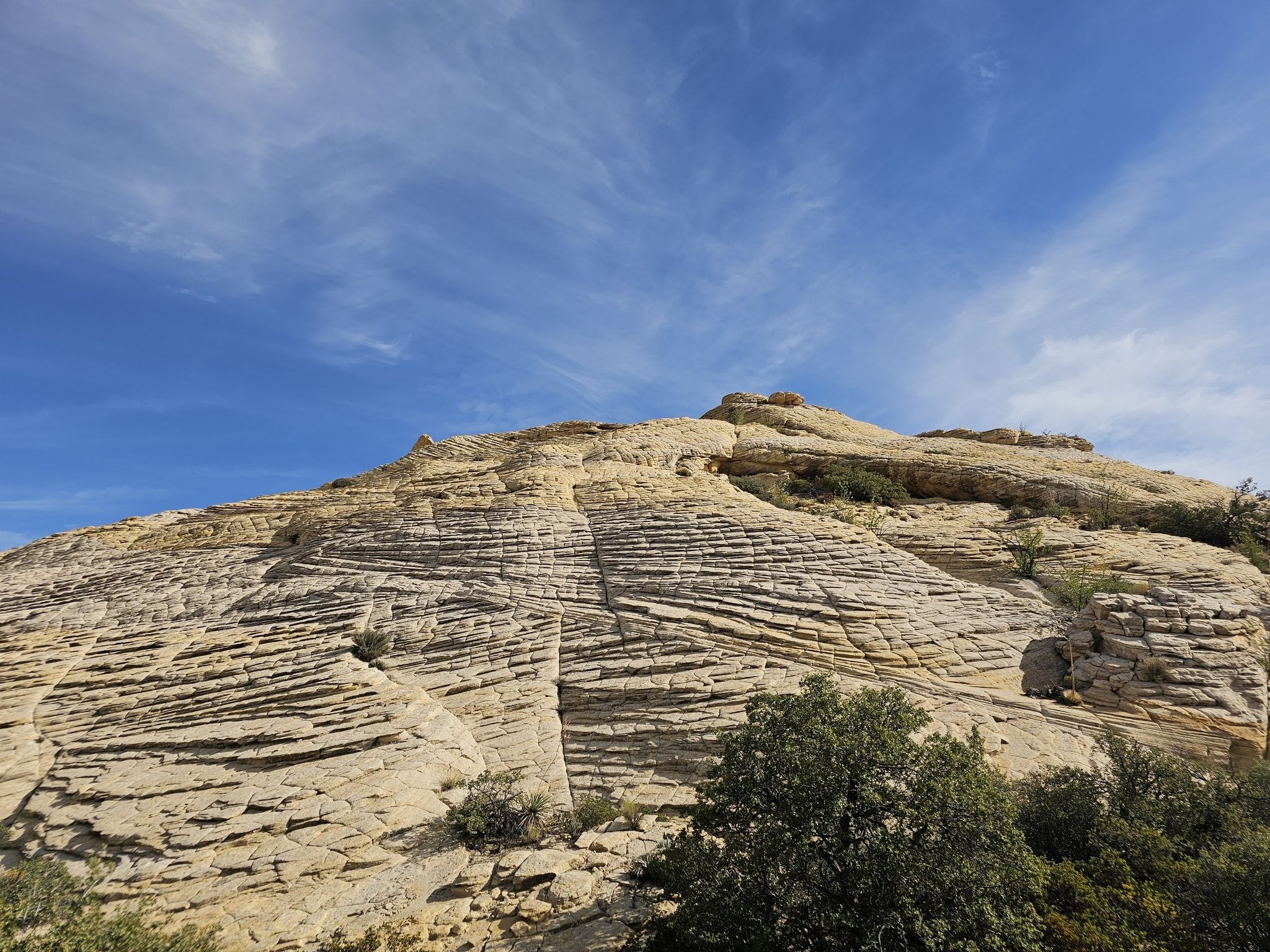 Layered rock formation under a bright blue sky with wispy clouds. - Gila Trail