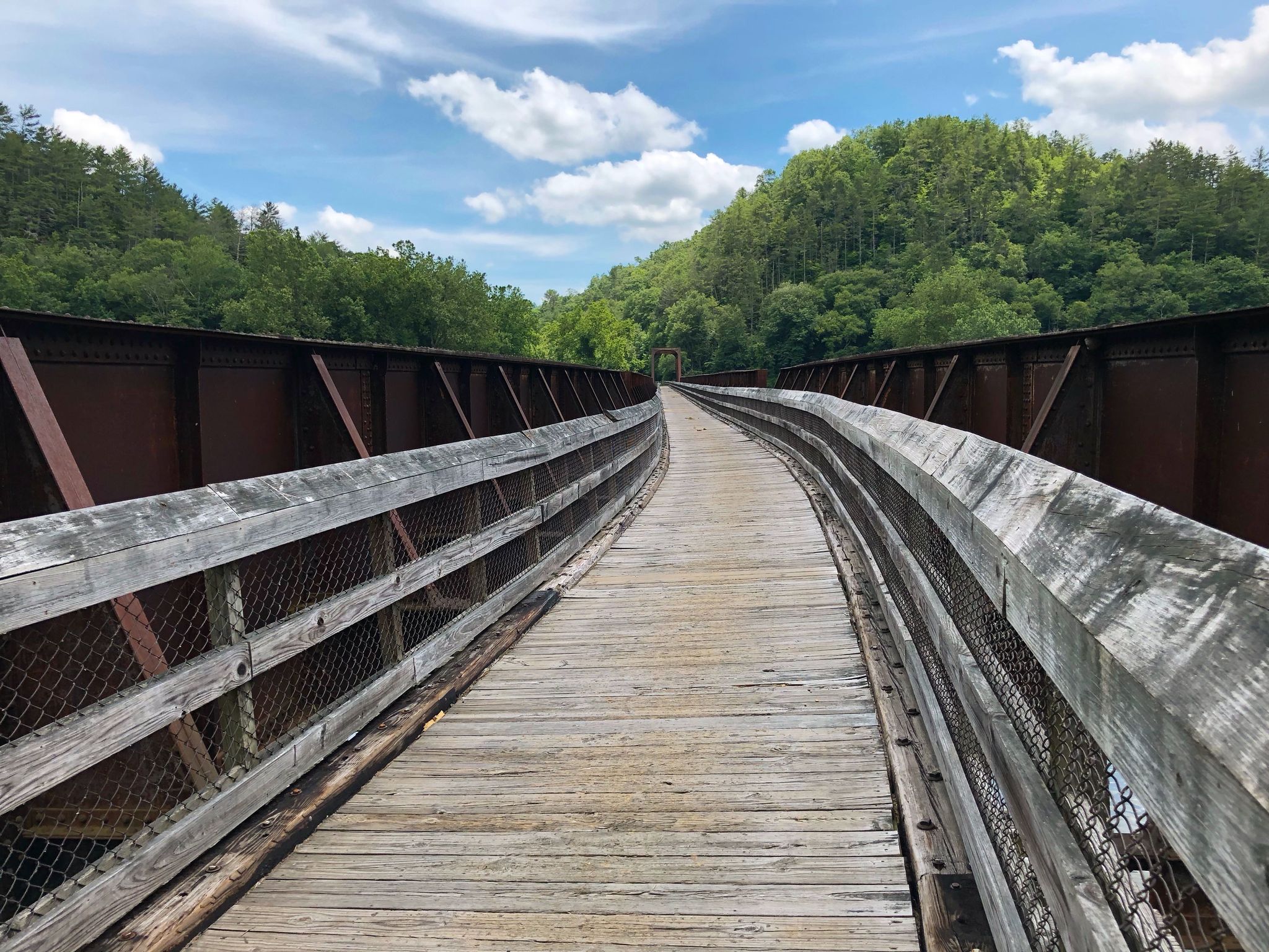 Long wooden and metal bridge over a valley, surrounded by green hills. - New River Trail: Fries Section