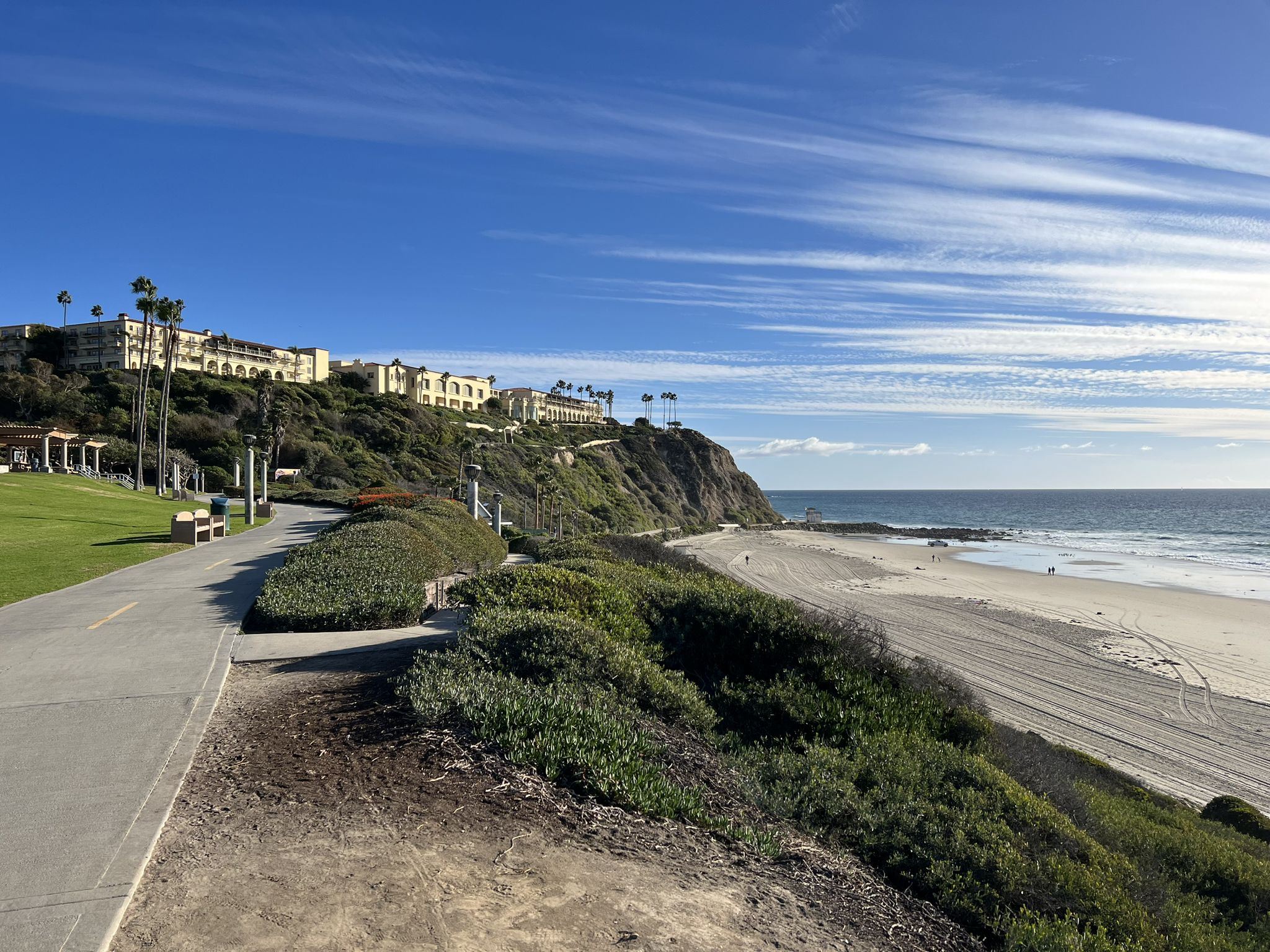 Coastal path overlooking a sunny beach, ocean, and cliffside buildings. - San Juan Creek and Salt Creek Trail Loop
