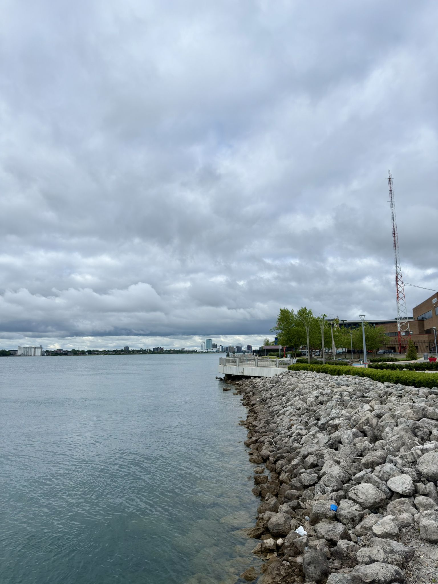 Overcast sky above a wide body of water and a rocky shoreline. - Grosse Pointe loop
