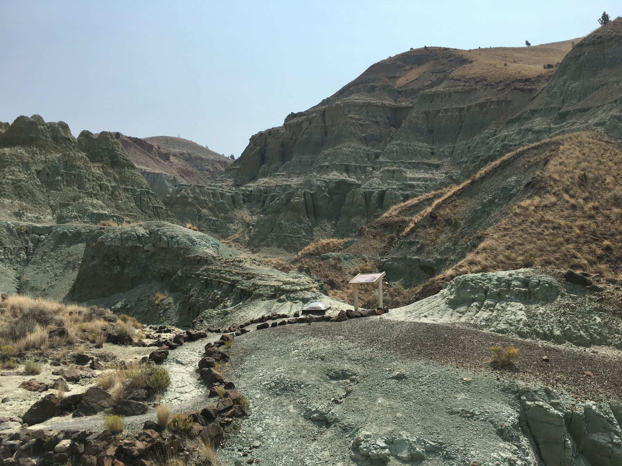 Winding path through a valley of green and brown rock formations, clear sky. - Blue Basin loop from Blue Basin