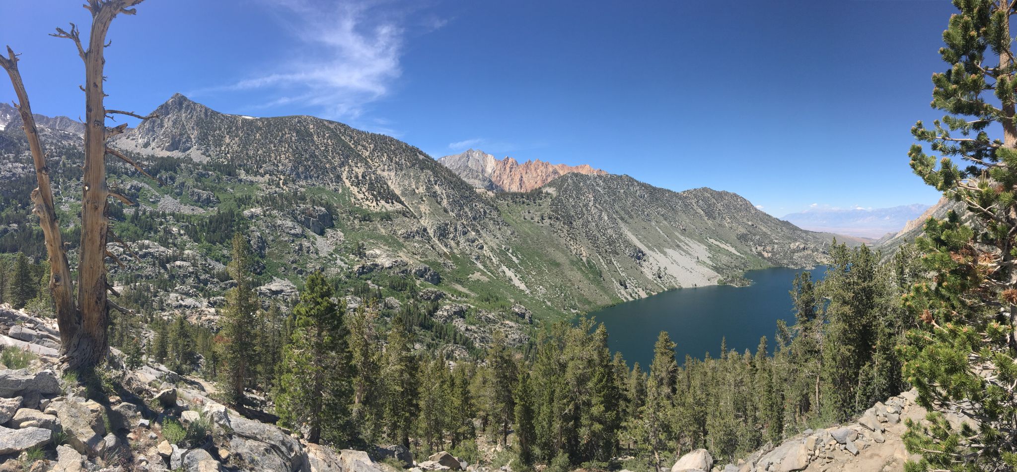 Panoramic view of a deep blue mountain lake surrounded by rugged, green peaks. - Sabrina Basin Trail
