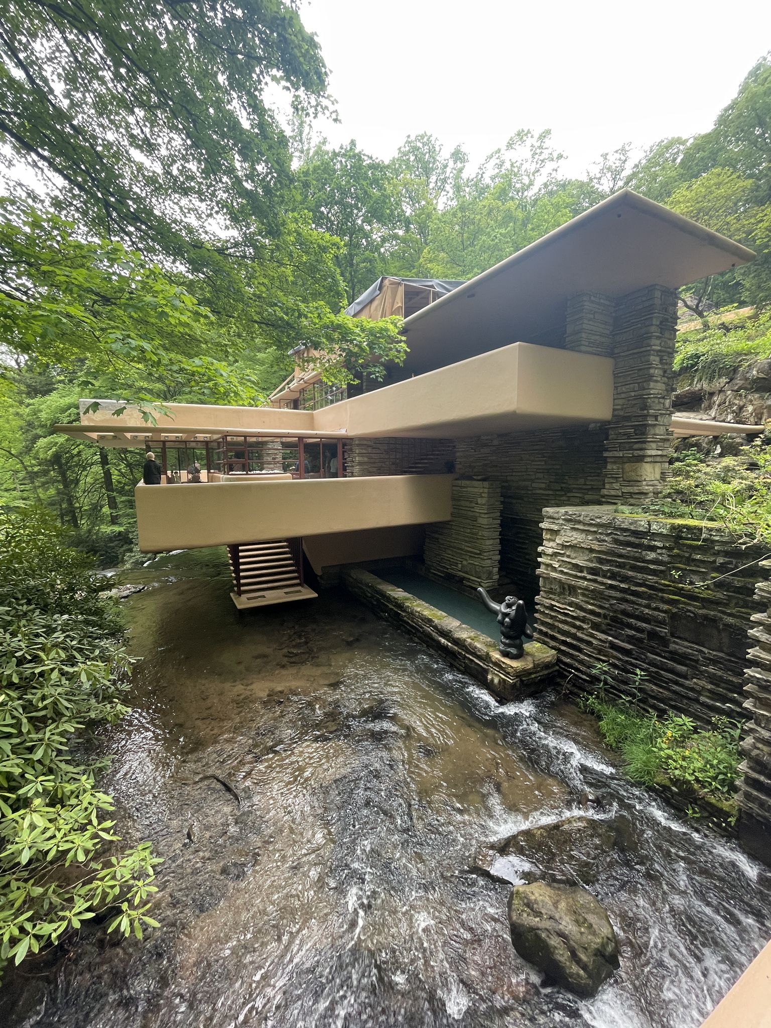 Modern house with balconies extending over a flowing stream in a green forest. - Black Loop Trail