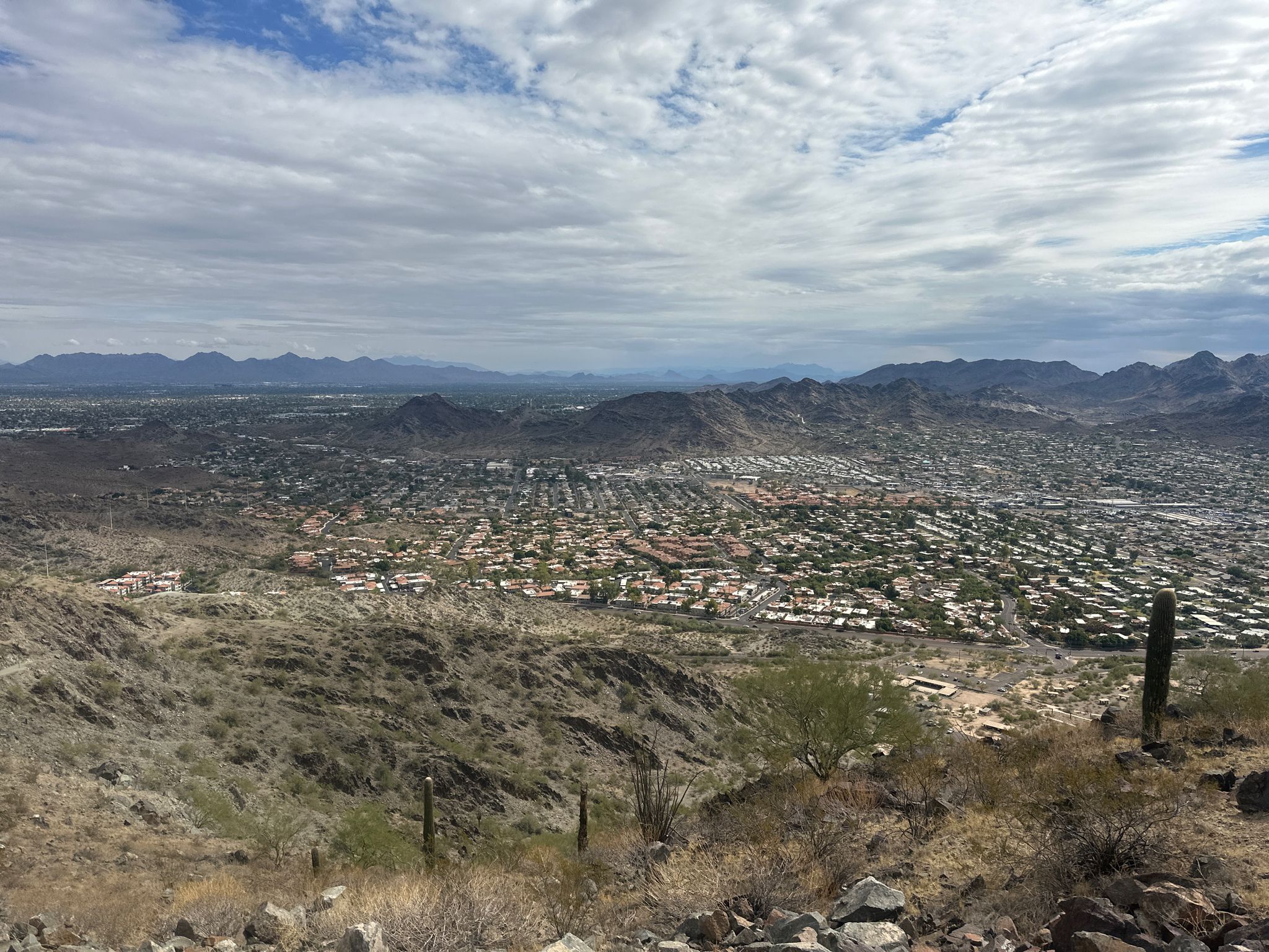Overcast view of a sprawling city nestled in a desert valley with distant mountains. - North Mountain loop from Sunnyslope Mountain