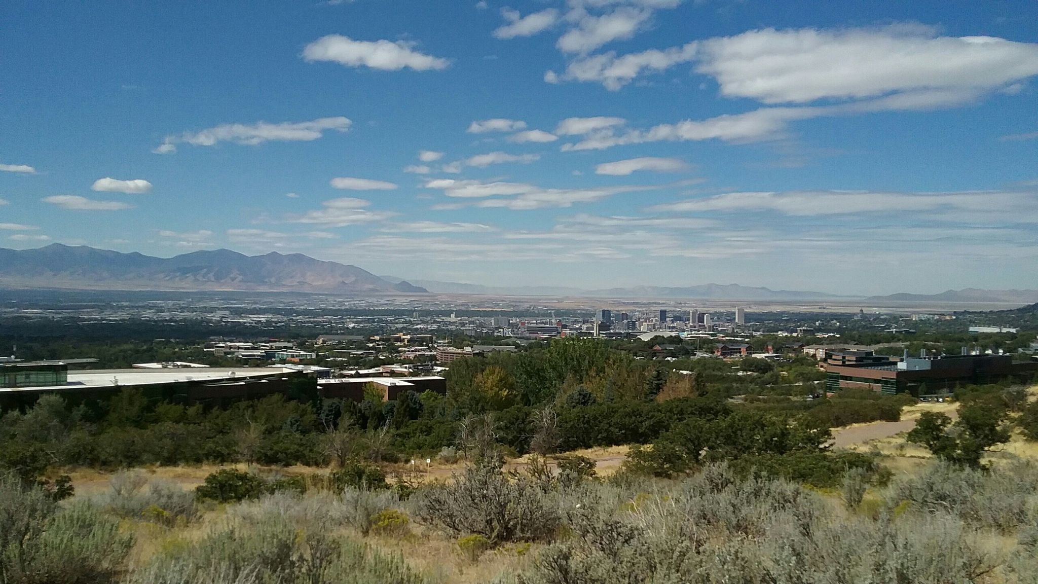 Distant city skyline and mountains under a bright, partly cloudy sky. - This Is the Place Monument – Utah's Hogle Zoo loop from This is the Place Monument