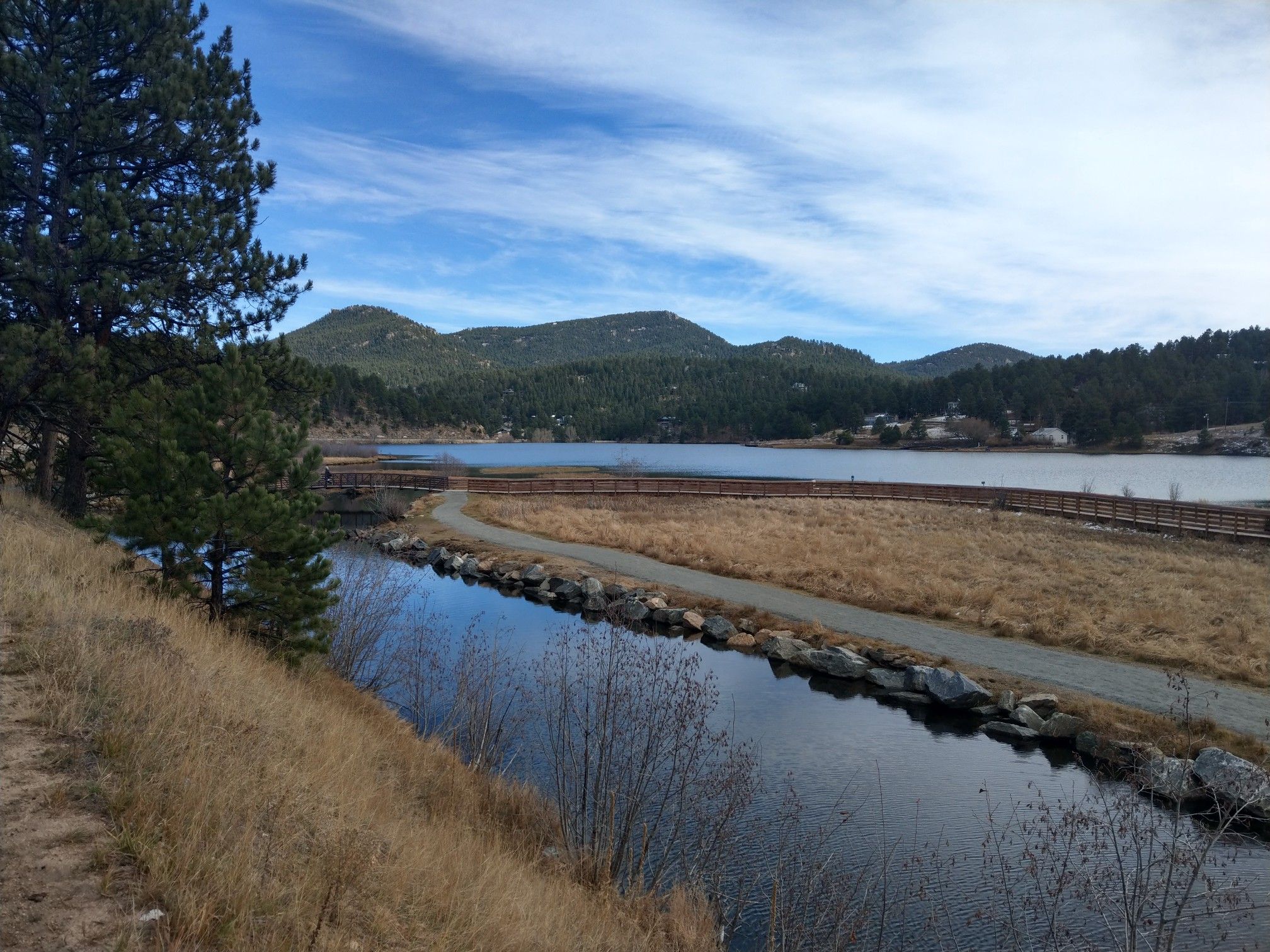 A calm lake and stream with mountains under a partly cloudy sky. - Evergreen and Witter Gulch loop