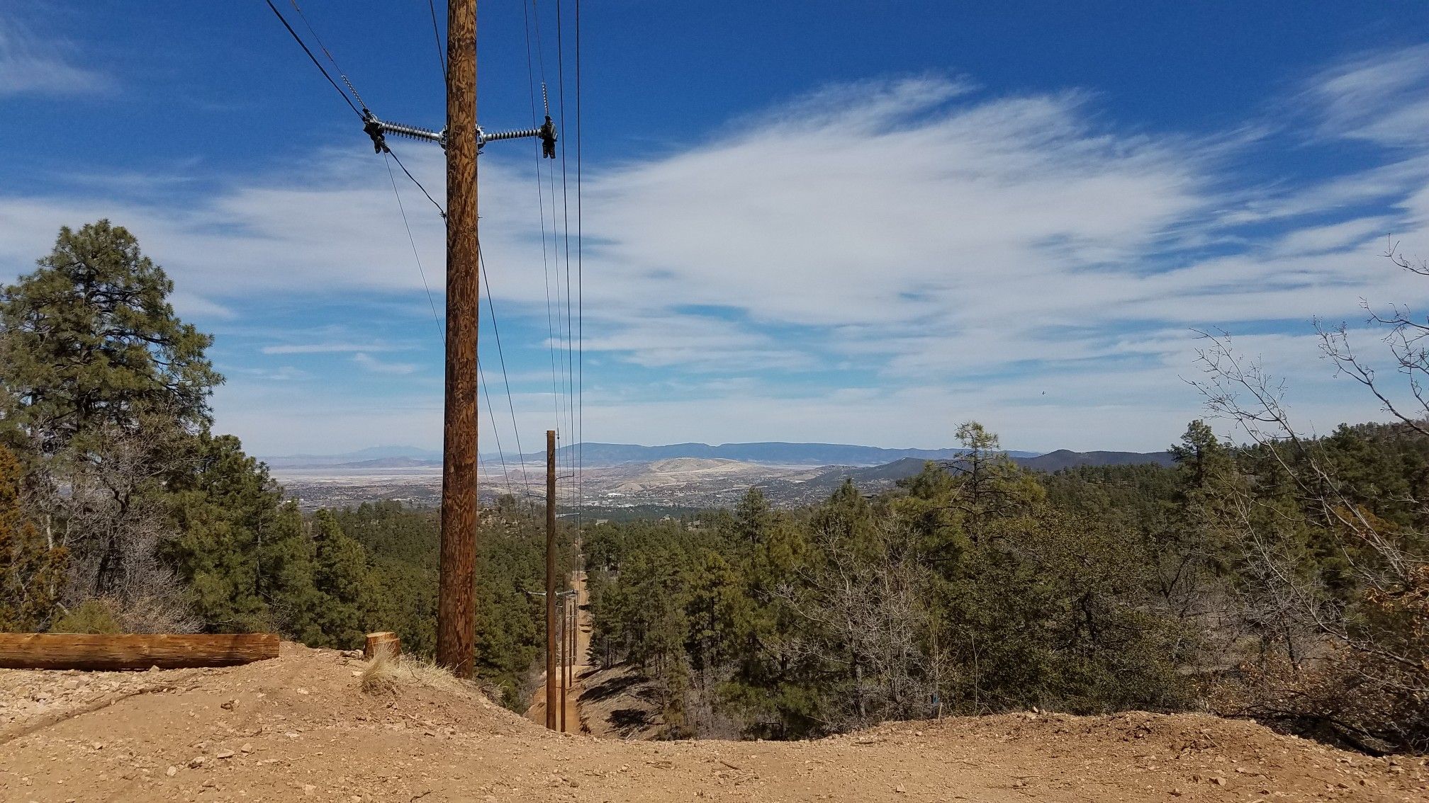 Utility pole and power lines over a forested valley under a blue sky. - Cold Spring Trail #393