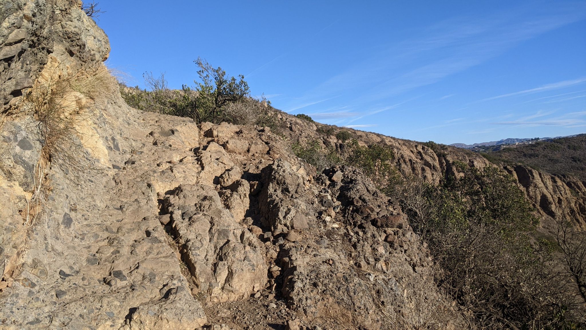 Rocky, rugged terrain on a hillside with sparse vegetation under a clear blue sky. - Canyon Overlook Trail to Wildwood Canyon Trail Loop