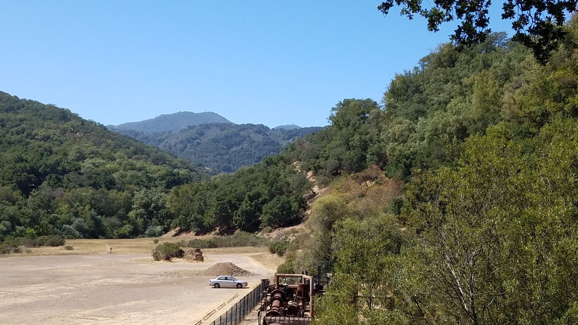 A wide valley with forested hills and a dirt clearing under a clear sky. - Deep Gulch, Castillero, Mine Hill, Prospect #3 and Randol Trail Loop
