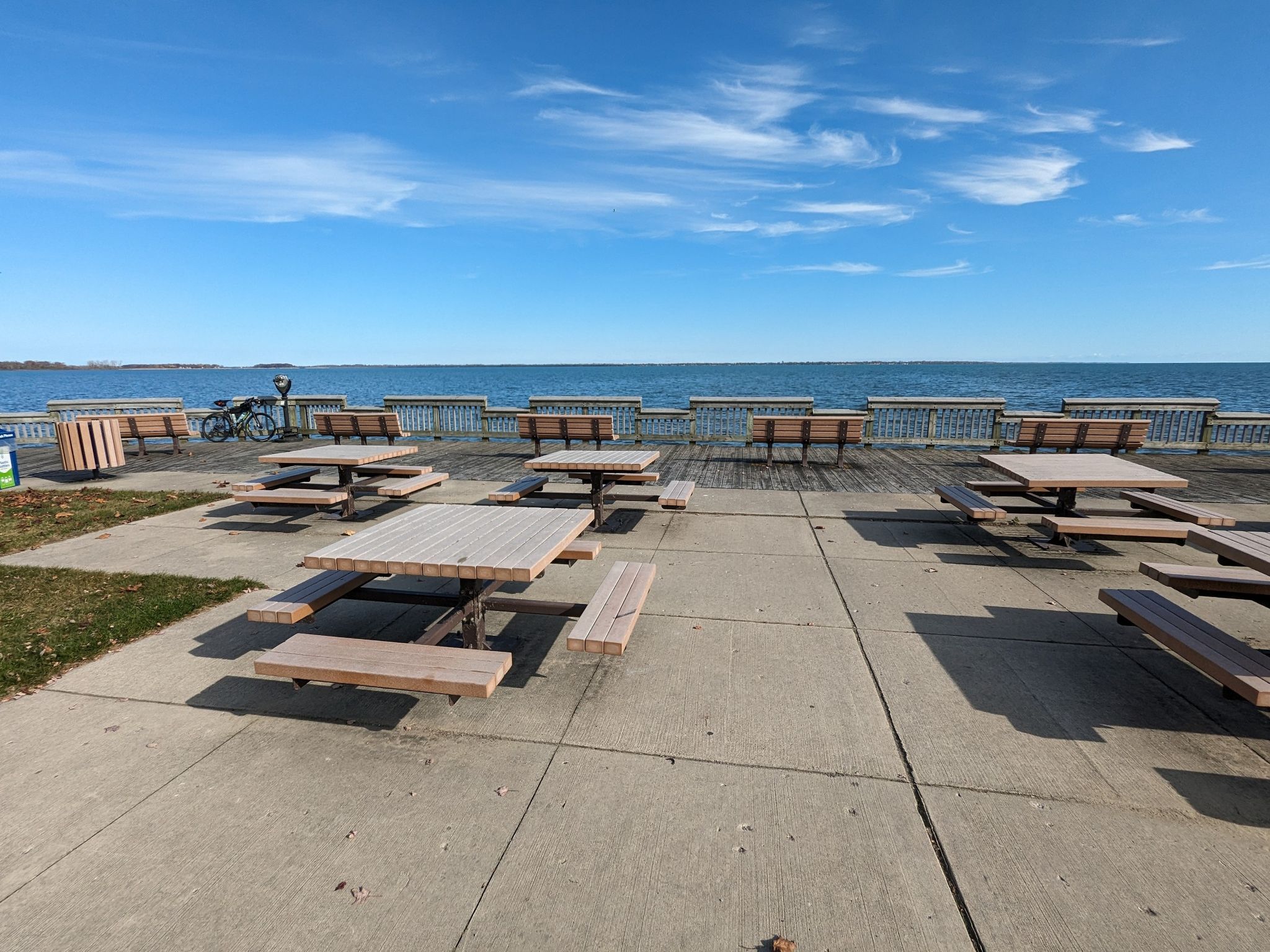 Picnic tables on a paved area overlooking a vast blue body of water. - Downriver Linked Greenways