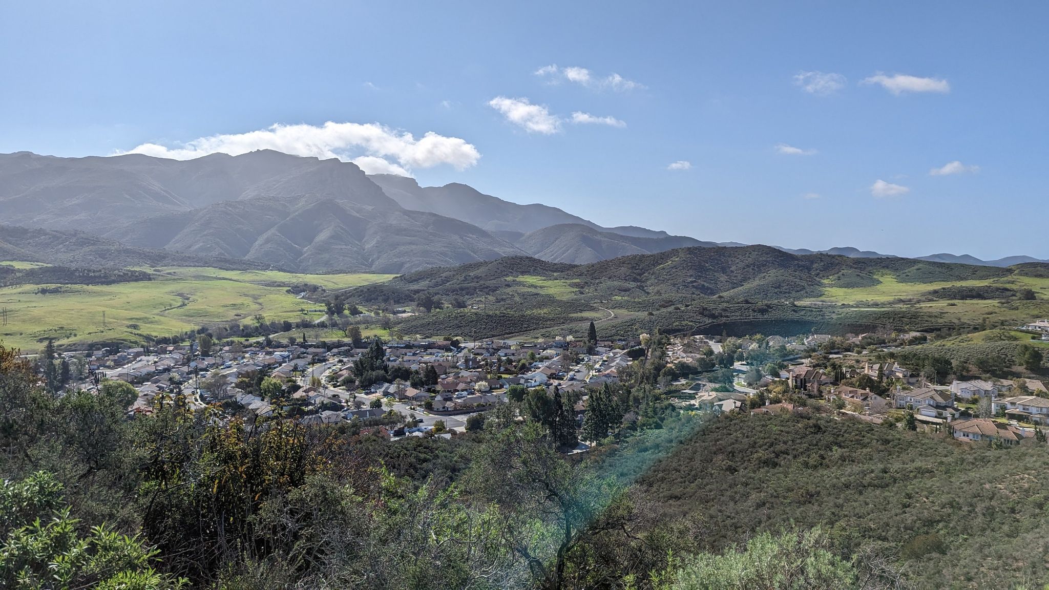 Bright view of a town in a valley, surrounded by mountains and green hills. - Twin Ponds via Portrero Ridge, Vista Del Mar, and Sierra Vista Trails