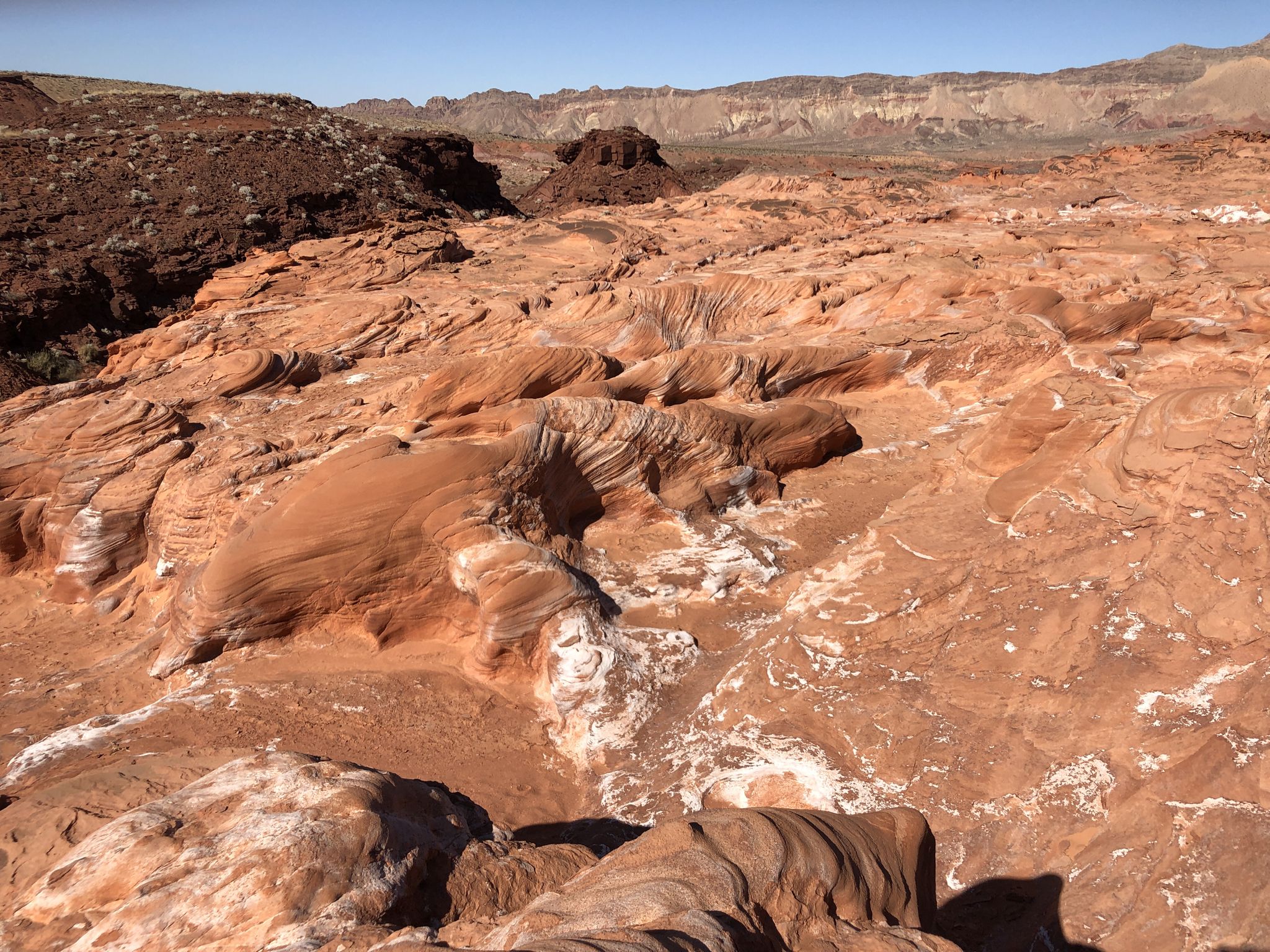 Wavy red rock formations with white patches under a clear blue sky. - Little Finland Loop