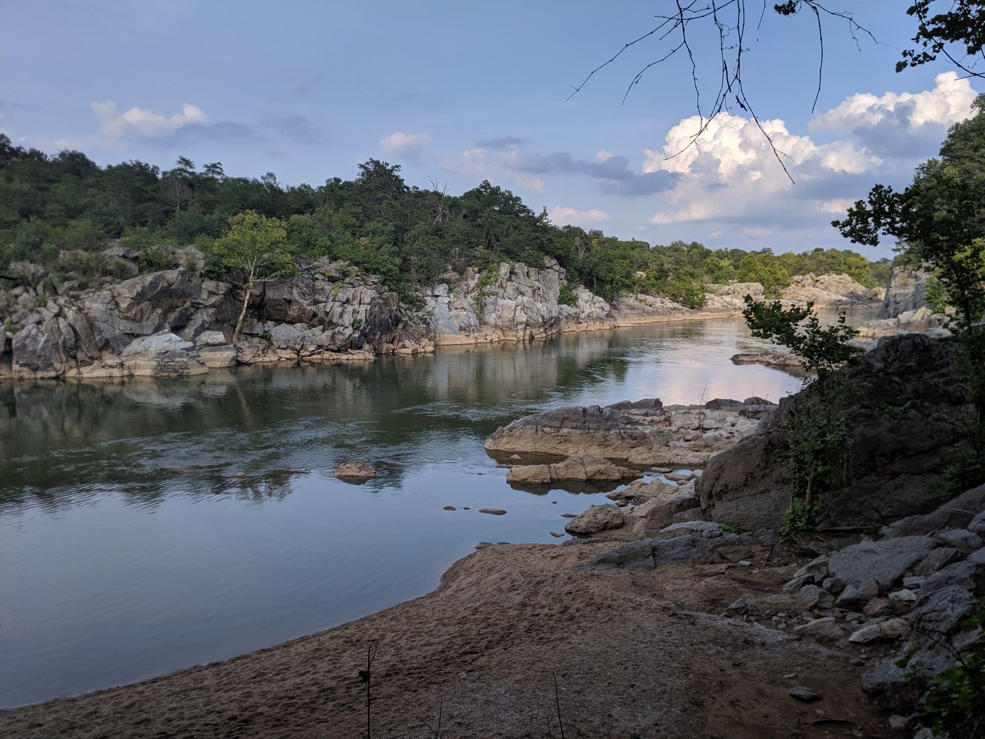 Wide river flows between rocky, forested banks under a partly cloudy sky. - Difficult Run, Ridge and River Trail Loop