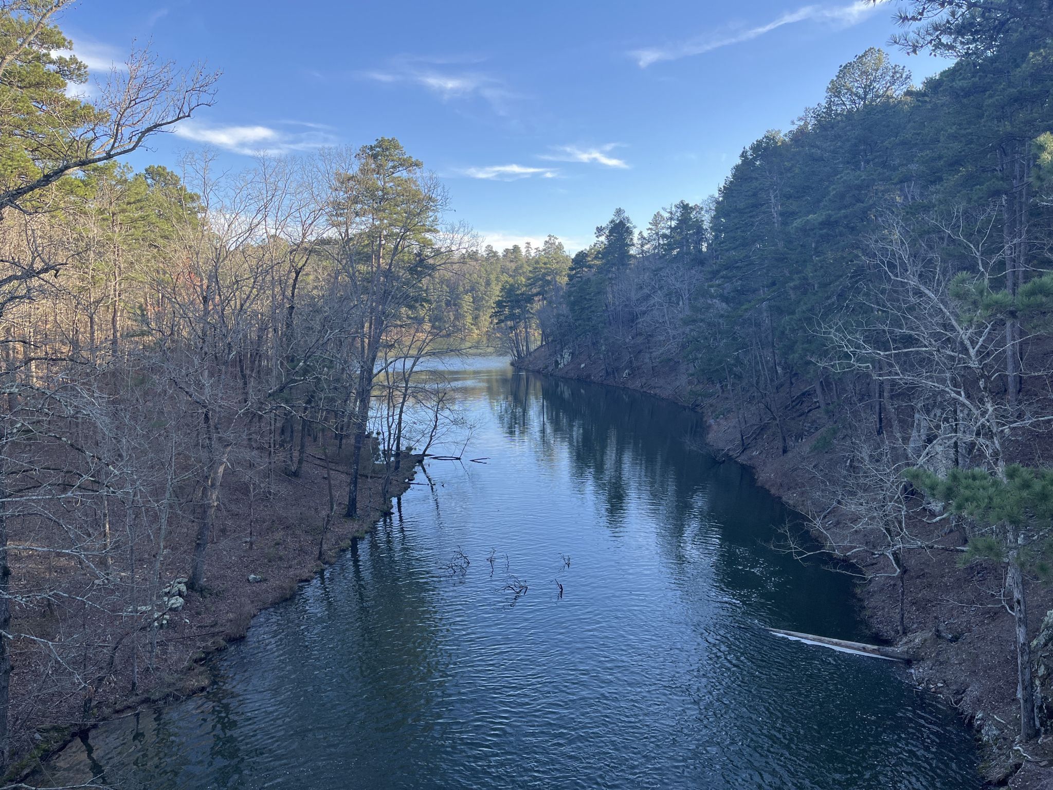 Narrow river flowing through a wooded valley under a bright blue sky. - Freeman and Ragnarok Loop