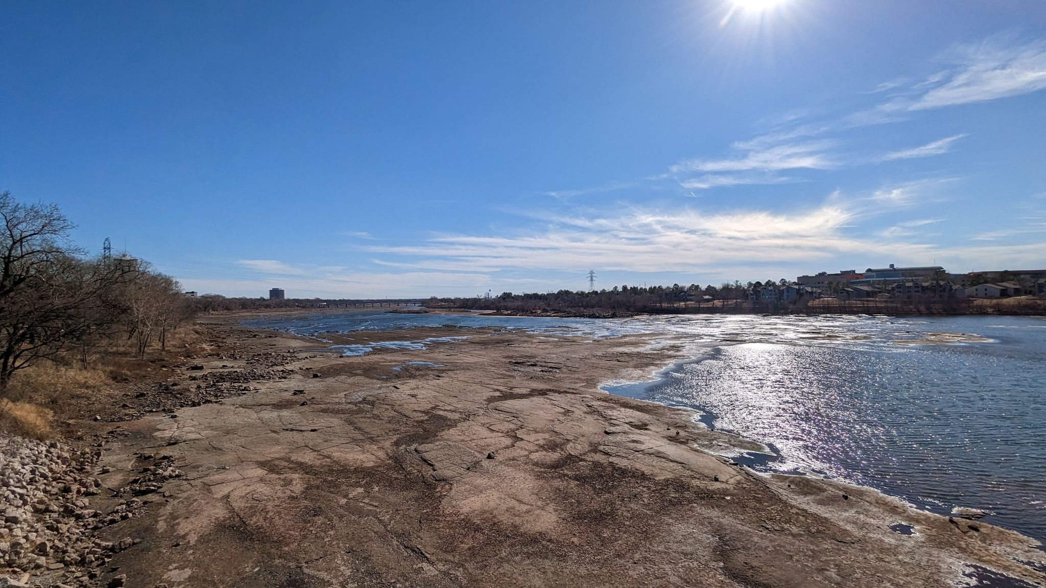 Wide river with exposed rocky banks under a bright sunny sky. - Arkansas River – Gathering Place Park loop from Memorial High School
