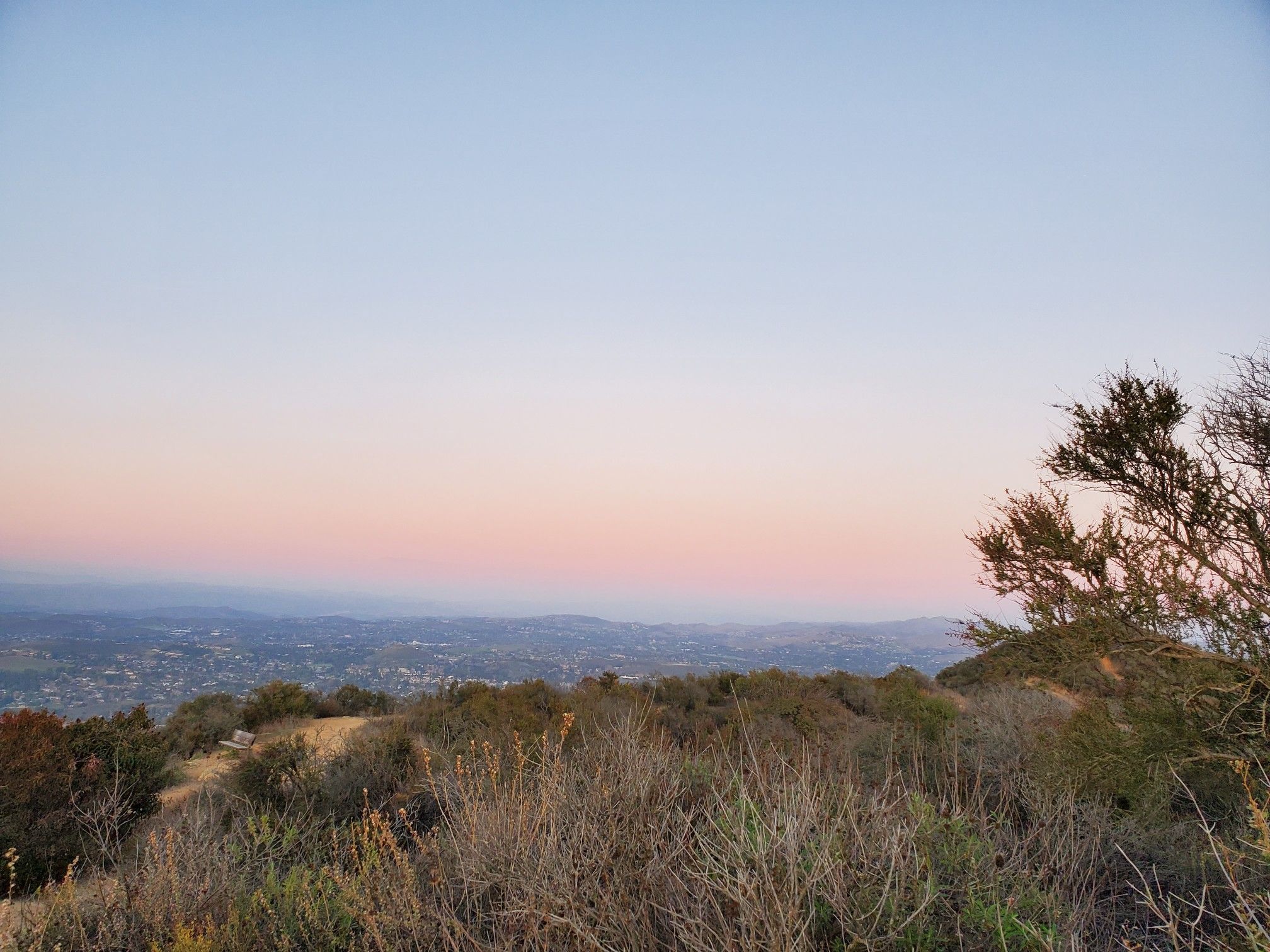 Panoramic view of hills and a distant town at dusk. - Los Robles Trail to Angel Vista