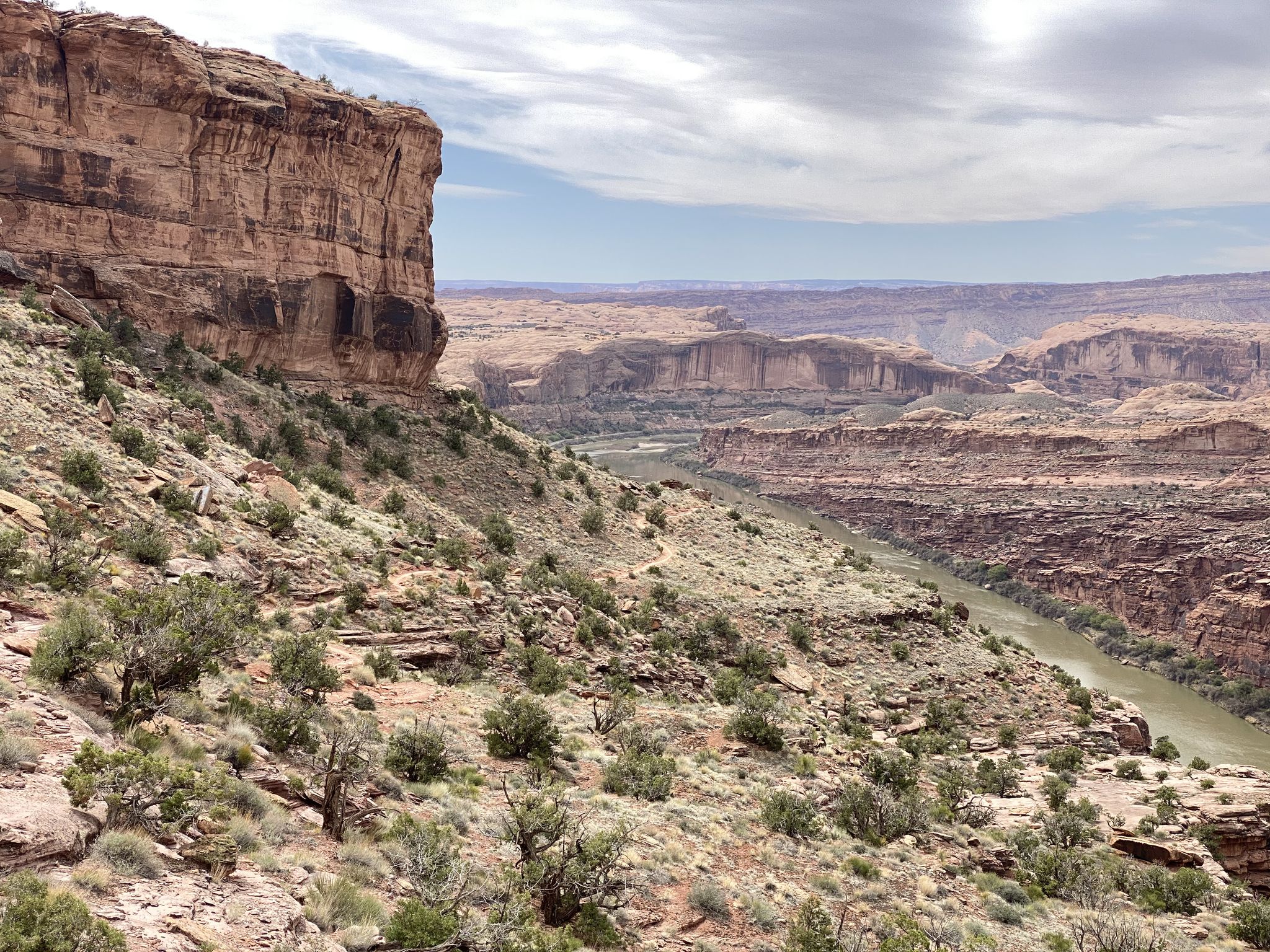 Large red rock cliff overlooking a winding river in a canyon. - The Whole Enchilada – Best of Moab MTB Trails