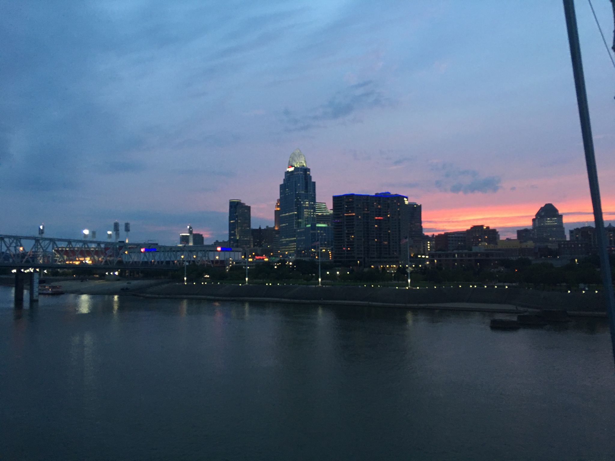 City skyline at dusk with a river in the foreground and a colorful sunset. - Ohio River Trail – Cincinnati Flying Pig Statues loop from Salem Heights