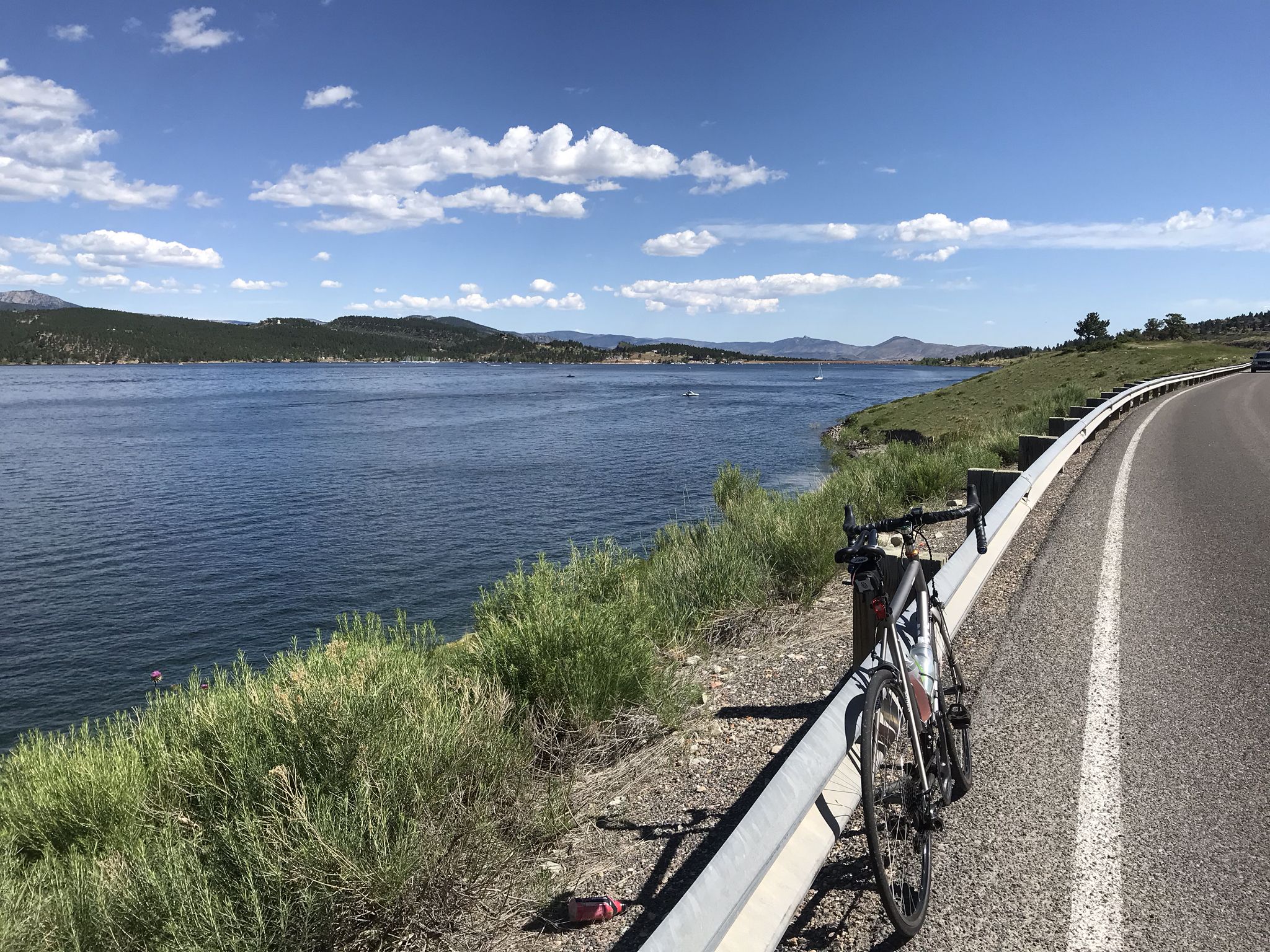 Bicycle parked by a large lake with distant hills under a sunny sky. - Carter Lake loop